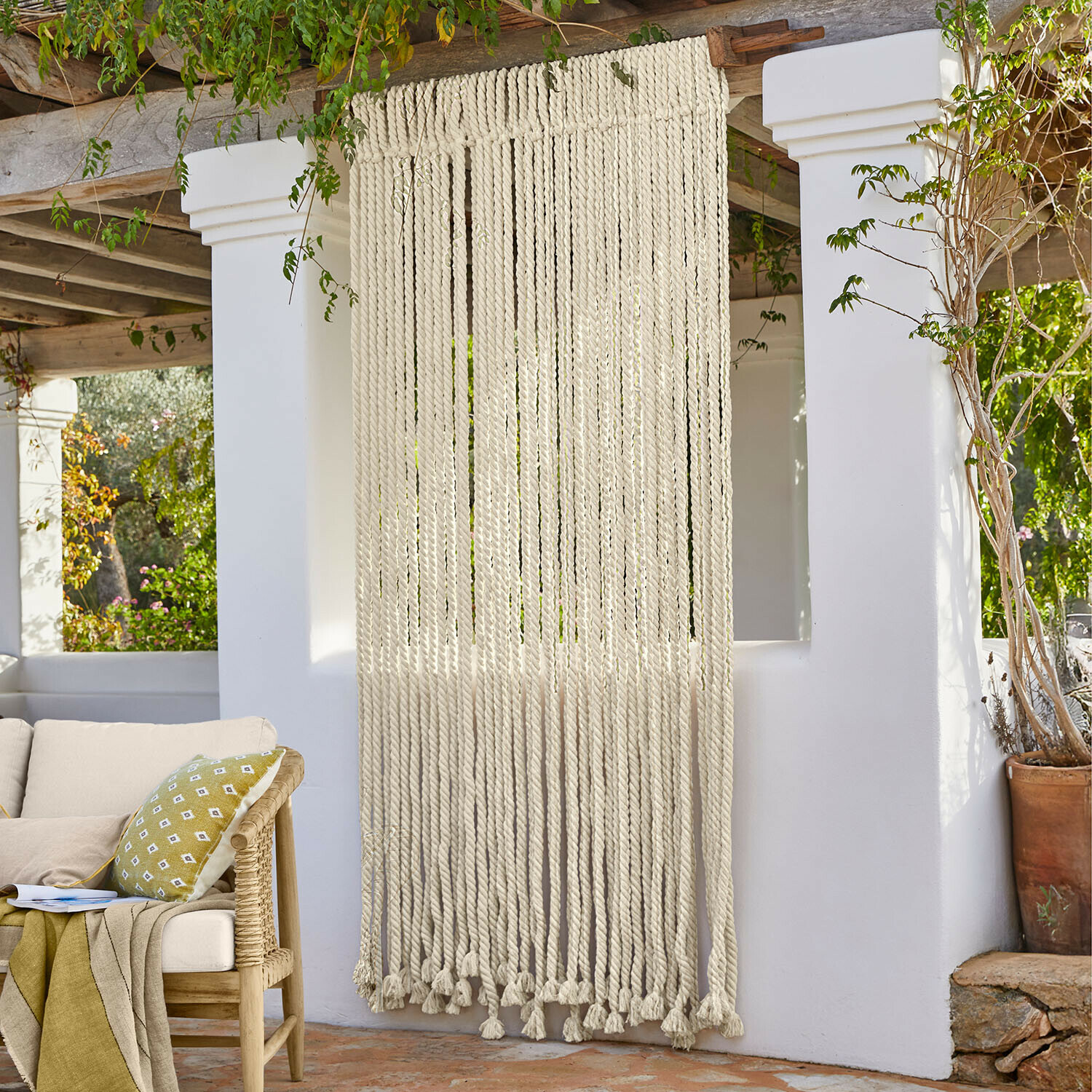 Decoratief gordijn van dikke witte katoenen touwen in boho-stijl op terras