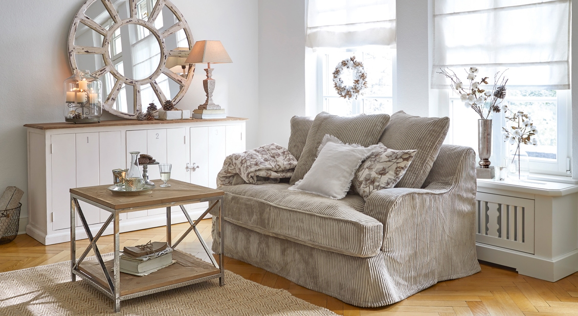 Beige ribfluwelen bank met kussens en houten salontafel in lichte, gezellige woonkamer