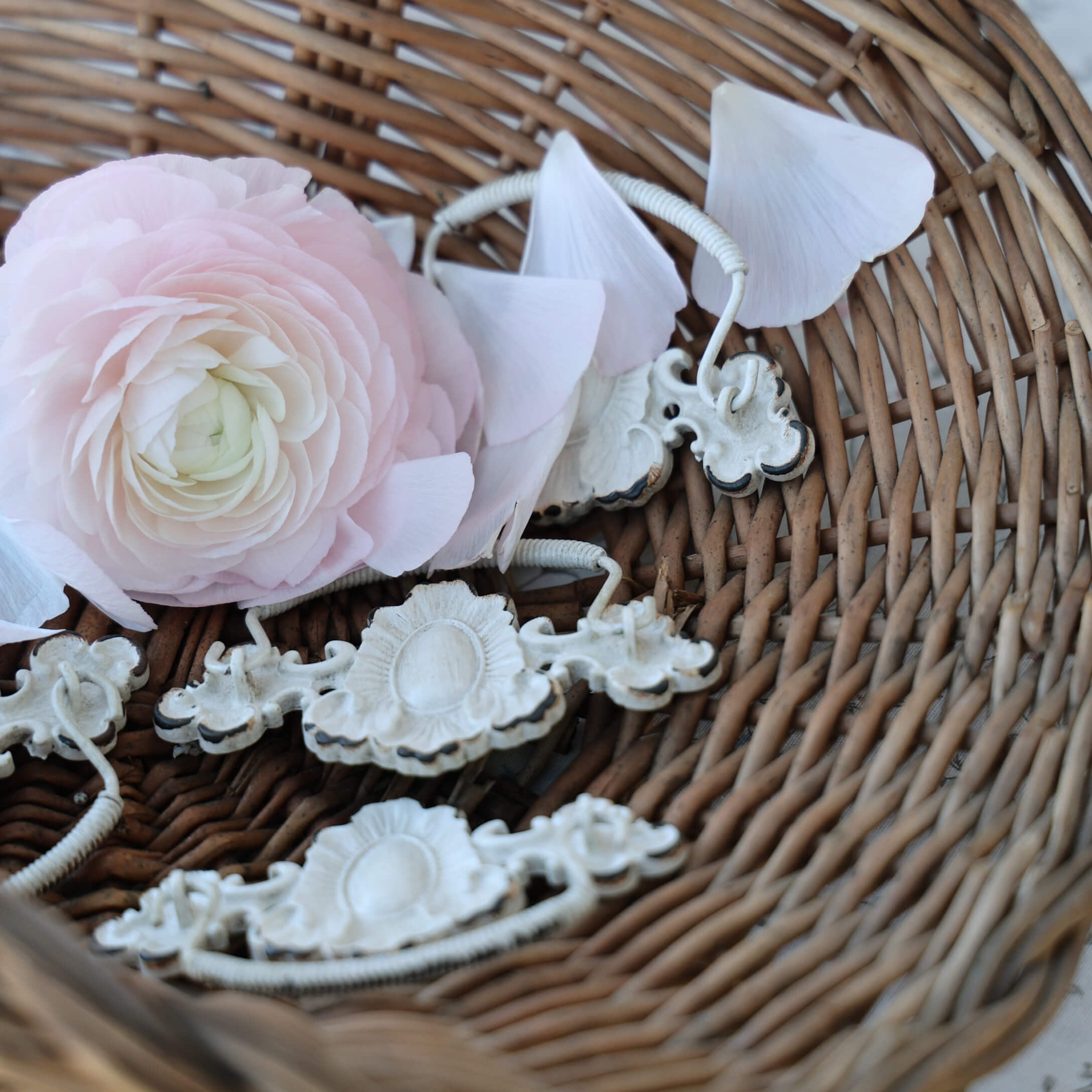 Delicate roze bloem en witte metalen handgrepen in een rieten mand, vintage interieurdecoratie