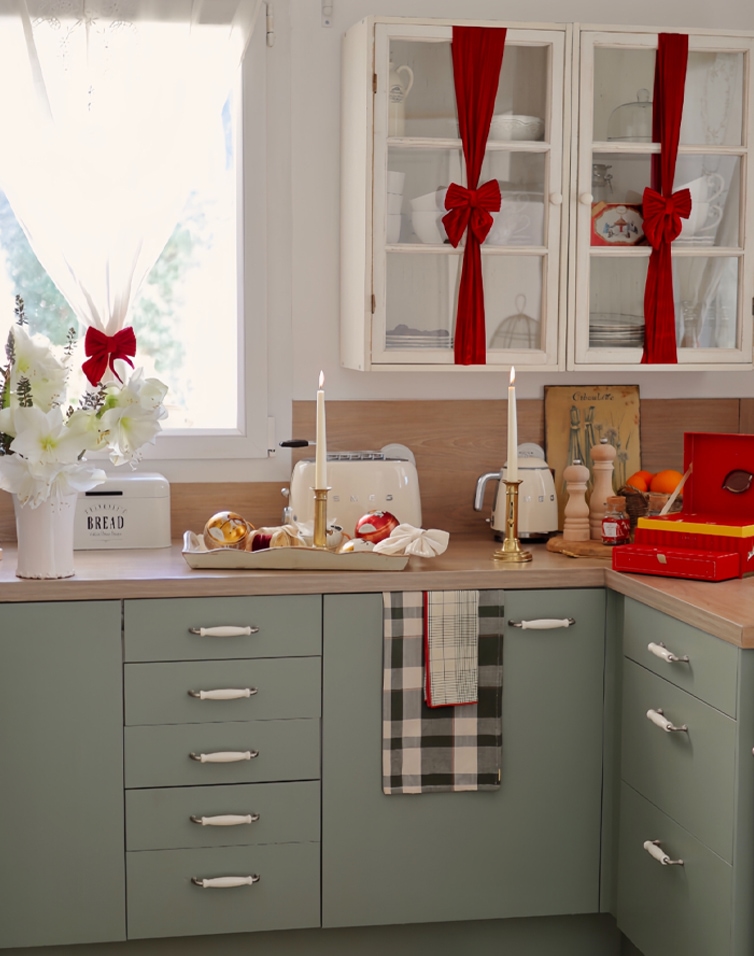 Keuken met groene kasten, witte gordijnen en rode strikken, gezellige kerstdecoratie