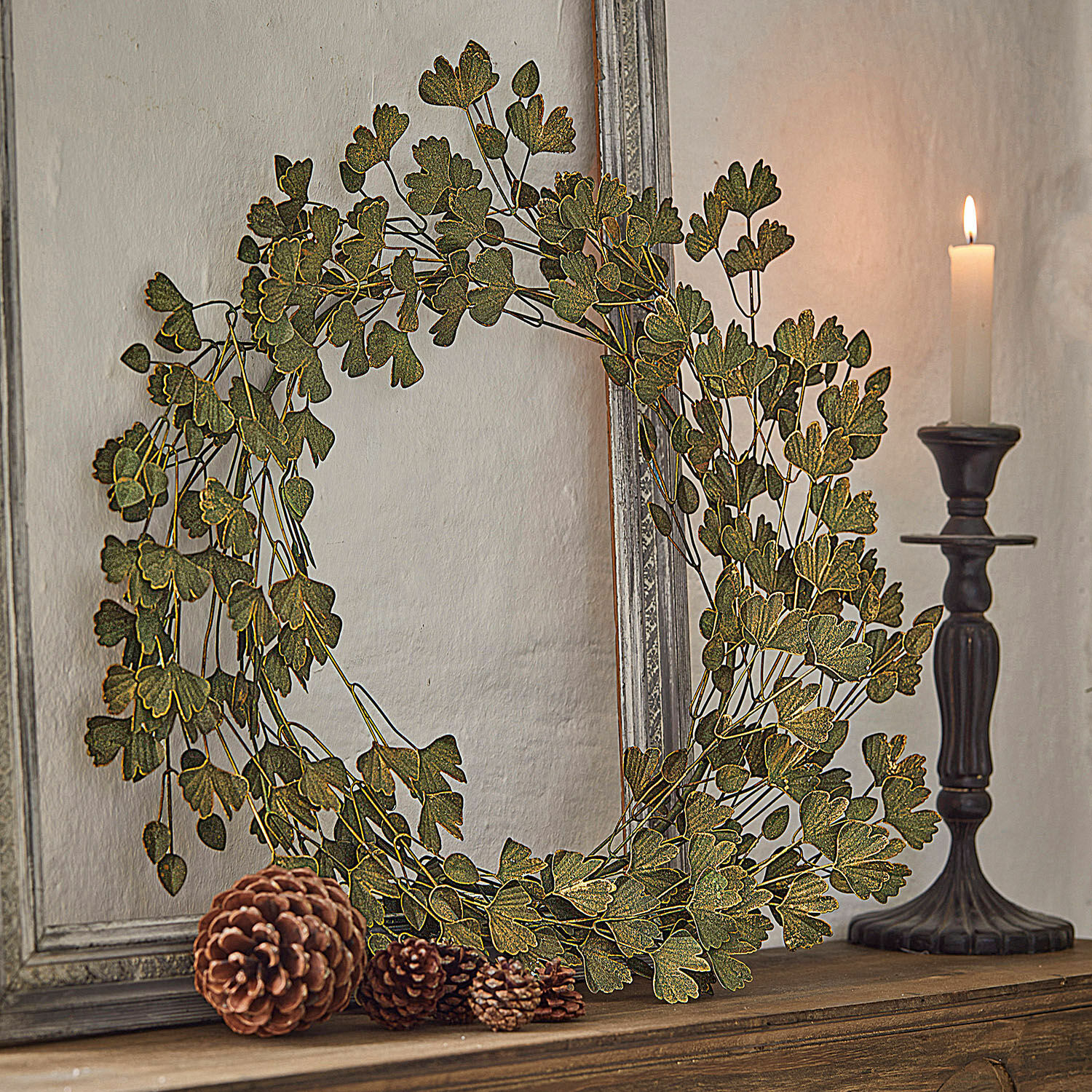 Krans Syrdarja Decoratieve krans van groene bladeren op houten plank met dennenappels en kaars