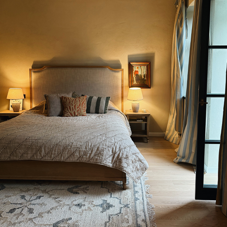 Gezellige slaapkamer met houten bed, beige dekbed, nachtlampjes en blauw gestreepte gordijnen