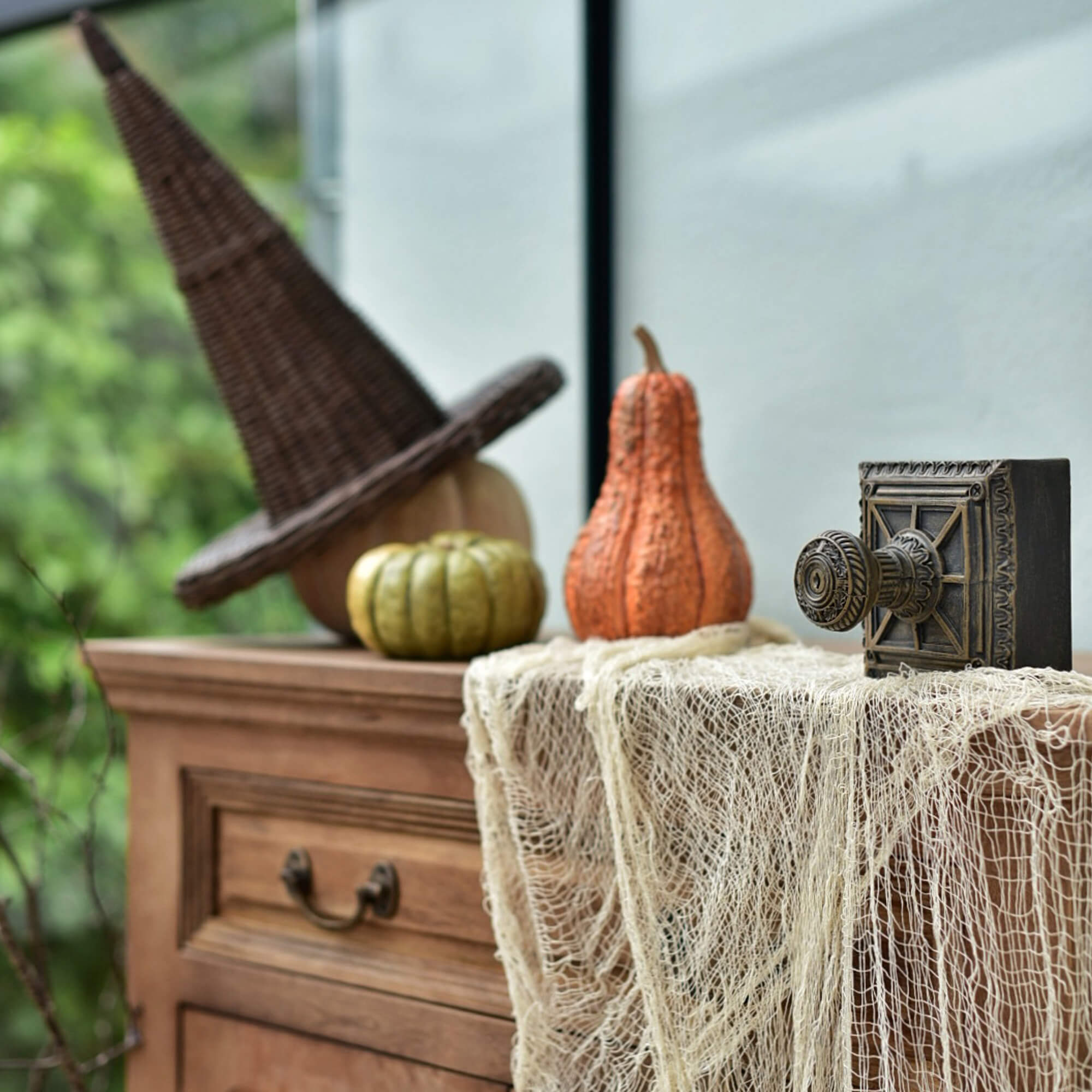 Houten ladekast met vlechtwerk heksenhoed en pompoenen als Halloweendecoratie