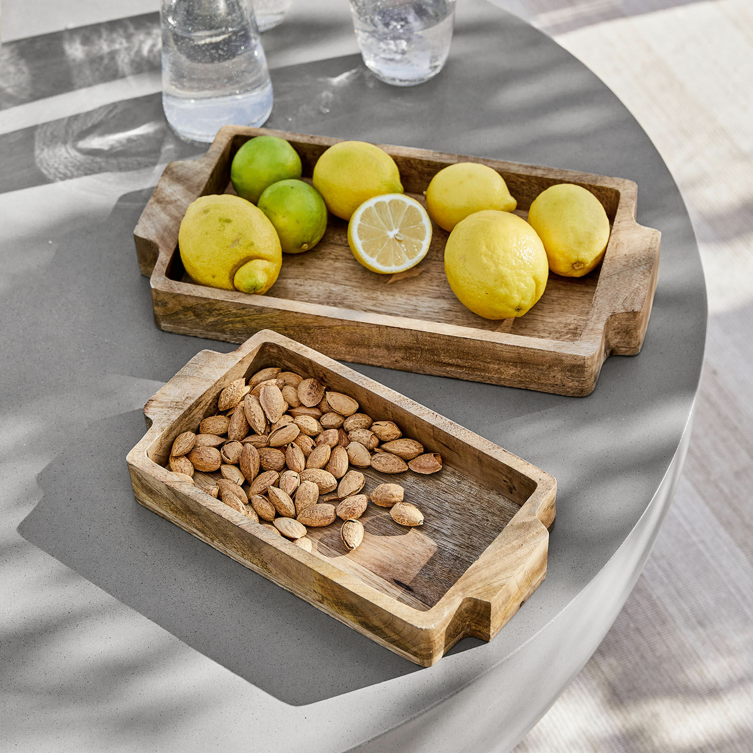 Dienblad set van 2 Buer Rechthoekige houten dienbladen met handvatten, één met citroenen, de ander met amandelen op grijze tafel