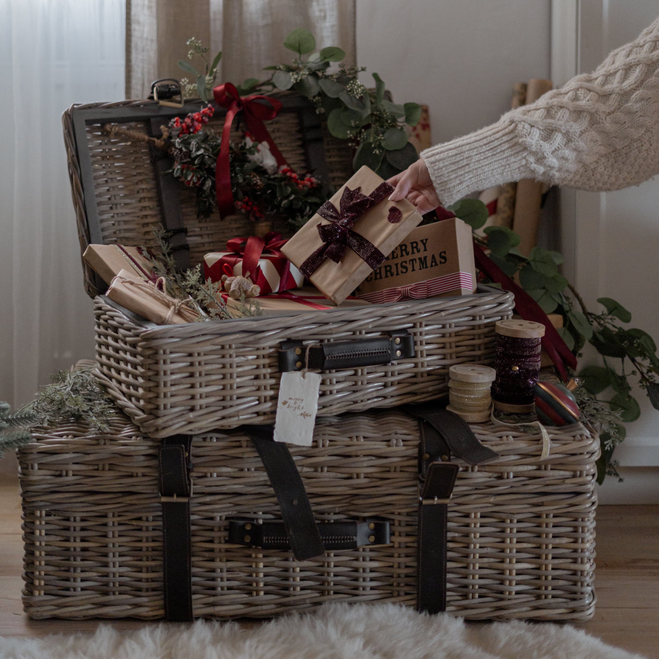 Twee grijze rieten manden met zwarte riemen, kerstcadeaus en decoraties in een gezellige kamer