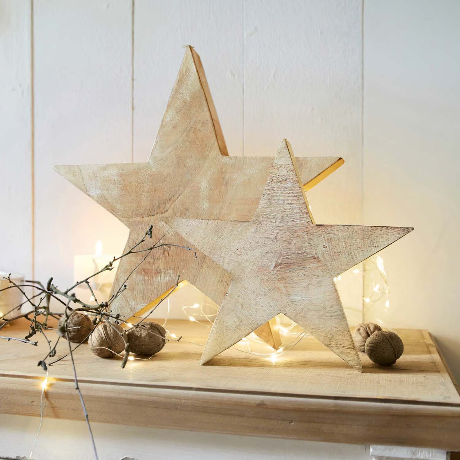 Houten sterren in natuurlijke kleur als decoratie op tafel met walnoten en LED-lichtjes