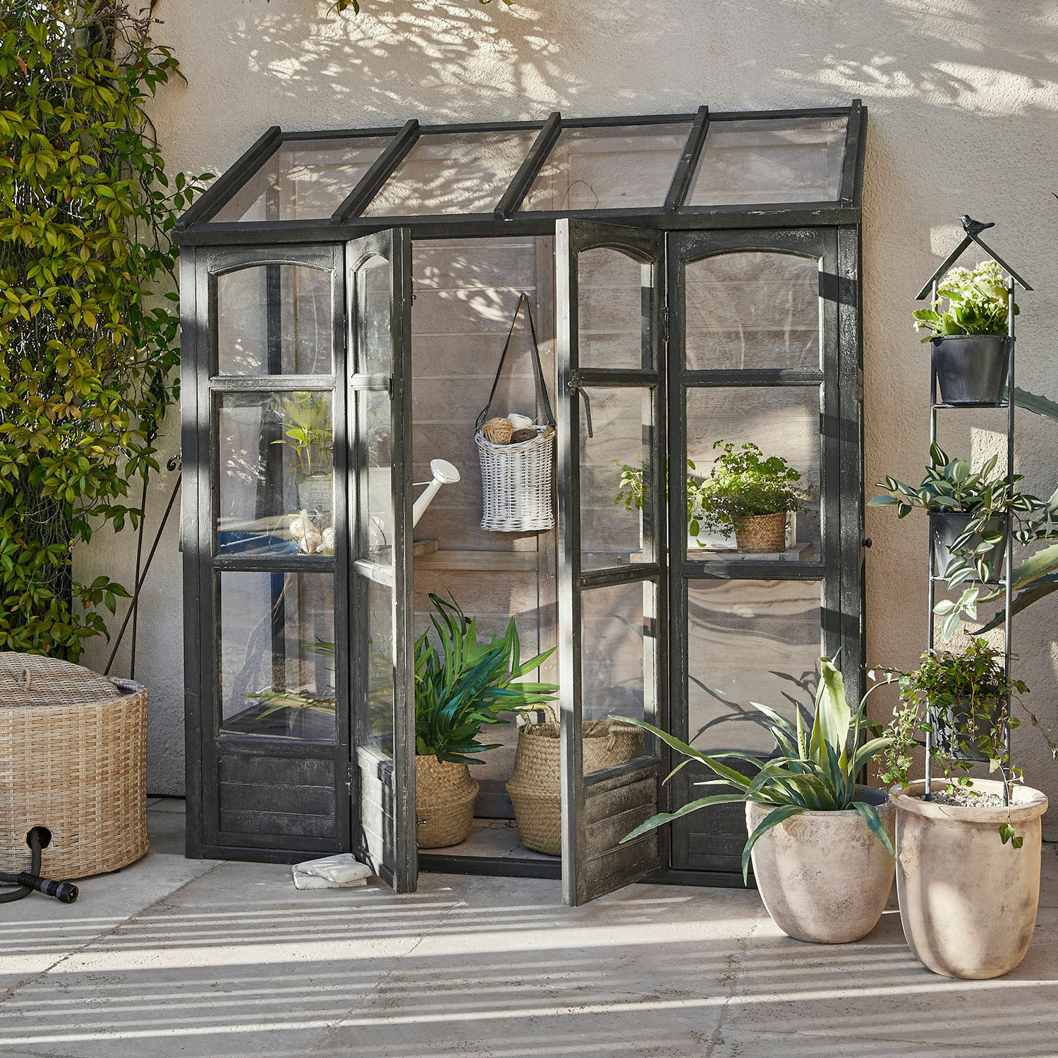 Plantenkas Abilenne Kleine tuinkas met zwart metalen frame en planten in potten op een zonnig terras