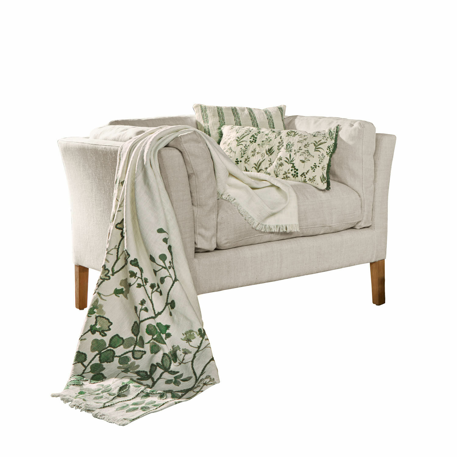 Fauteuil Lourvière Beige stoffen bank met groene kussens en decoratief deken met plantenmotief