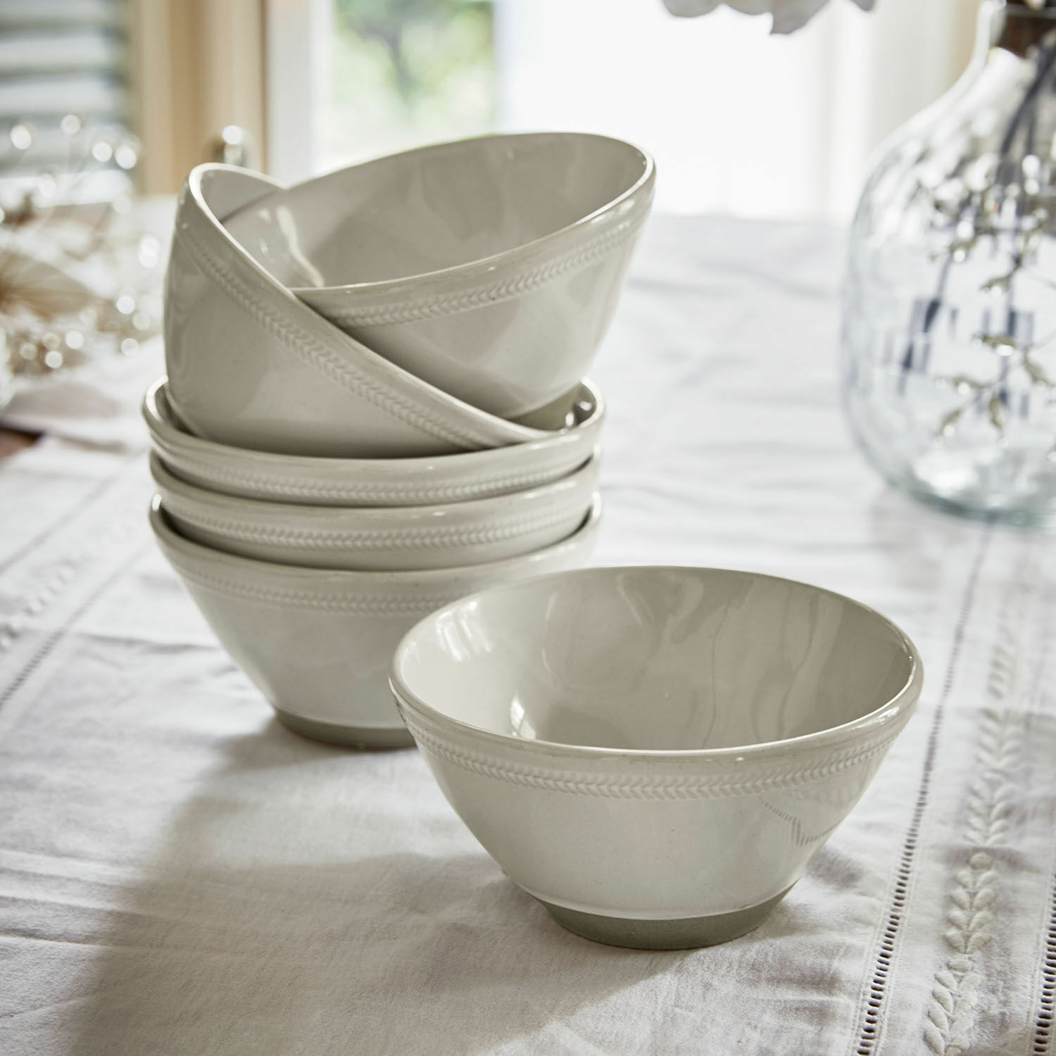 Set witte keramische kommen met fijn patroon aan de rand op een tafel met tafelkleed