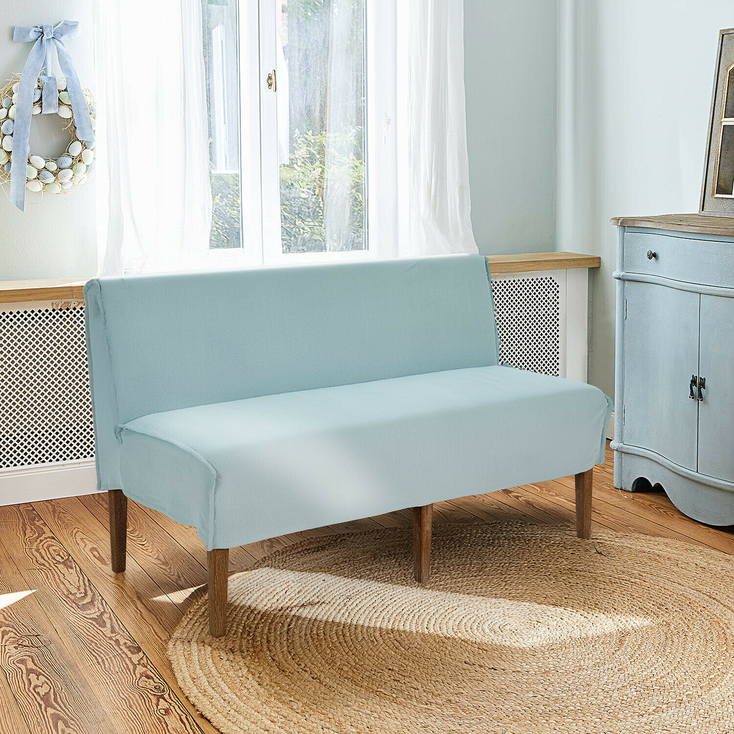 Keukenbank Vinterfjord Lichtblauwe katoenen bankhoes met houten poten in lichte woonkamer met jute vloerkleed