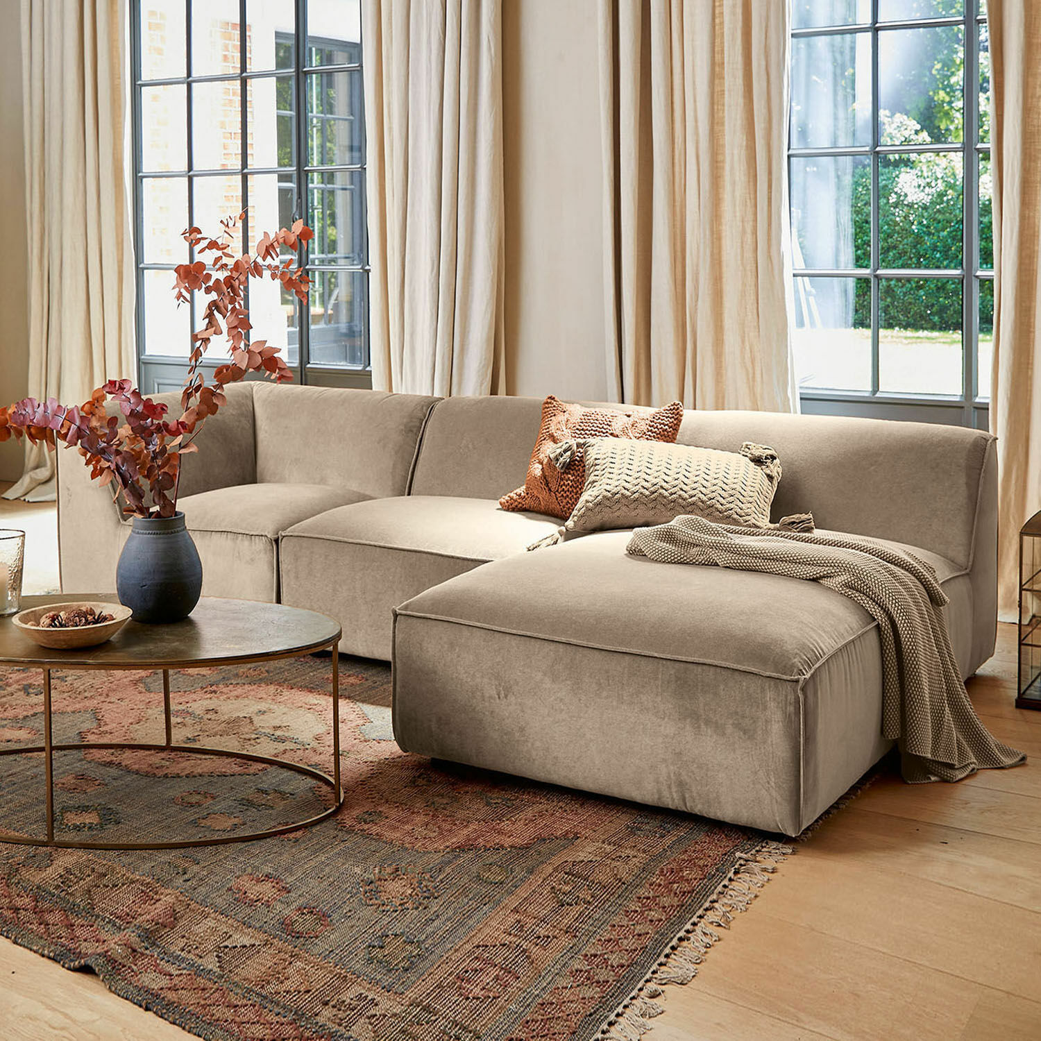 Bank McLean Beige hoekbank van zachte stof in stijlvolle woonkamer met vloerkleed en ronde salontafel