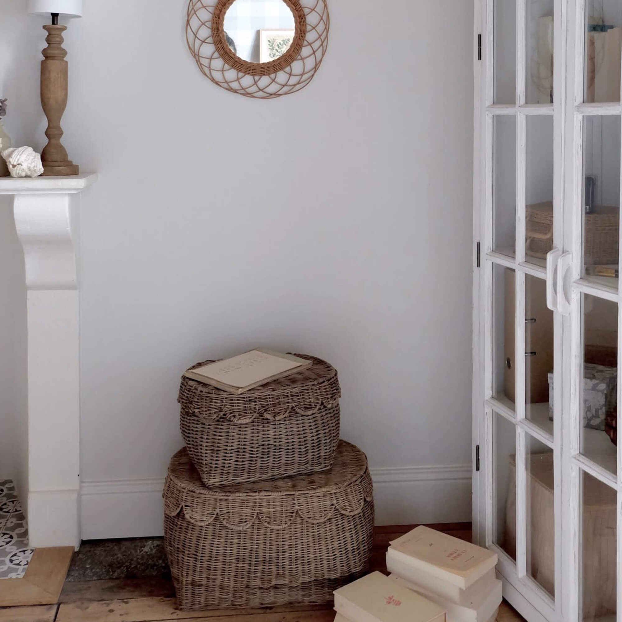 Twee natuurlijke rieten manden op houten vloer naast witte kast met gestapelde boeken