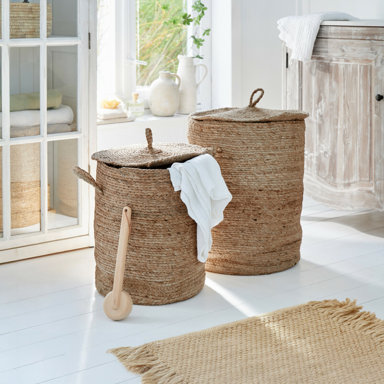 Twee ronde wasmanden van natuurlijke jute in beige kleur in een lichte badkamer