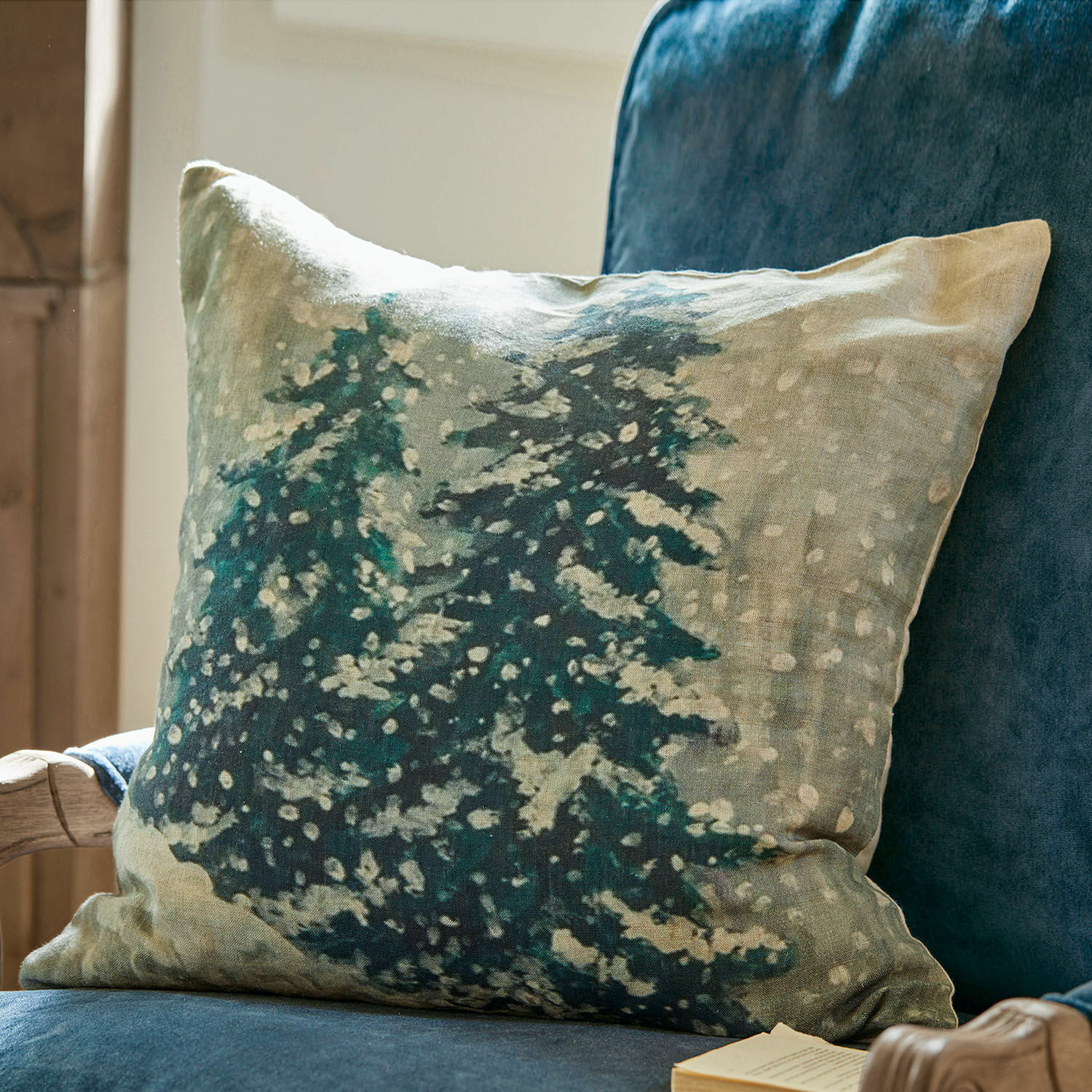 Kussenhoes Mierta Decoratief linnen kussen met groene dennenbomenprint op beige achtergrond op een blauwe stoel