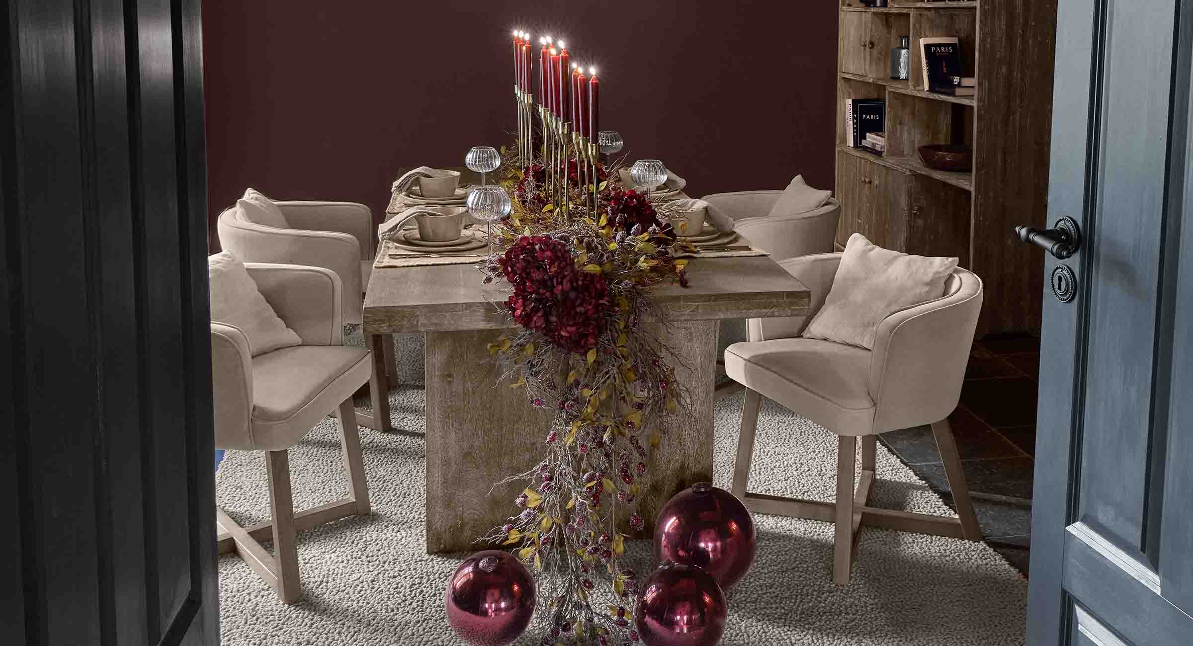 Elegante eettafel met beige stoelen en feestelijke rode decoratie met brandende kaarsen