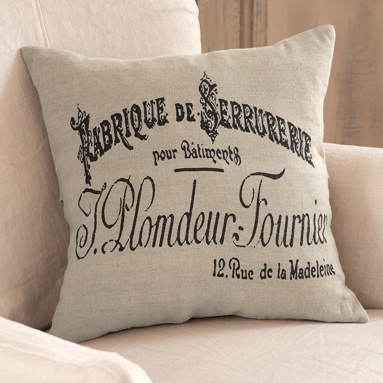 Kussenhoes Darby Beige linnen kussen met zwarte Franse print op lichte bank, interieurdecoratie