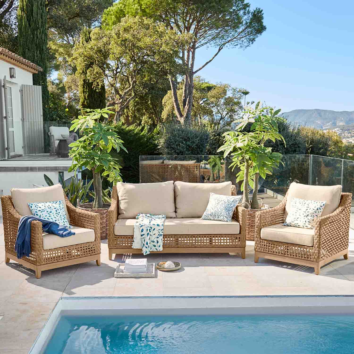 Tuinmeubelset van natuurlijk rattan met beige kussens bij het zwembad