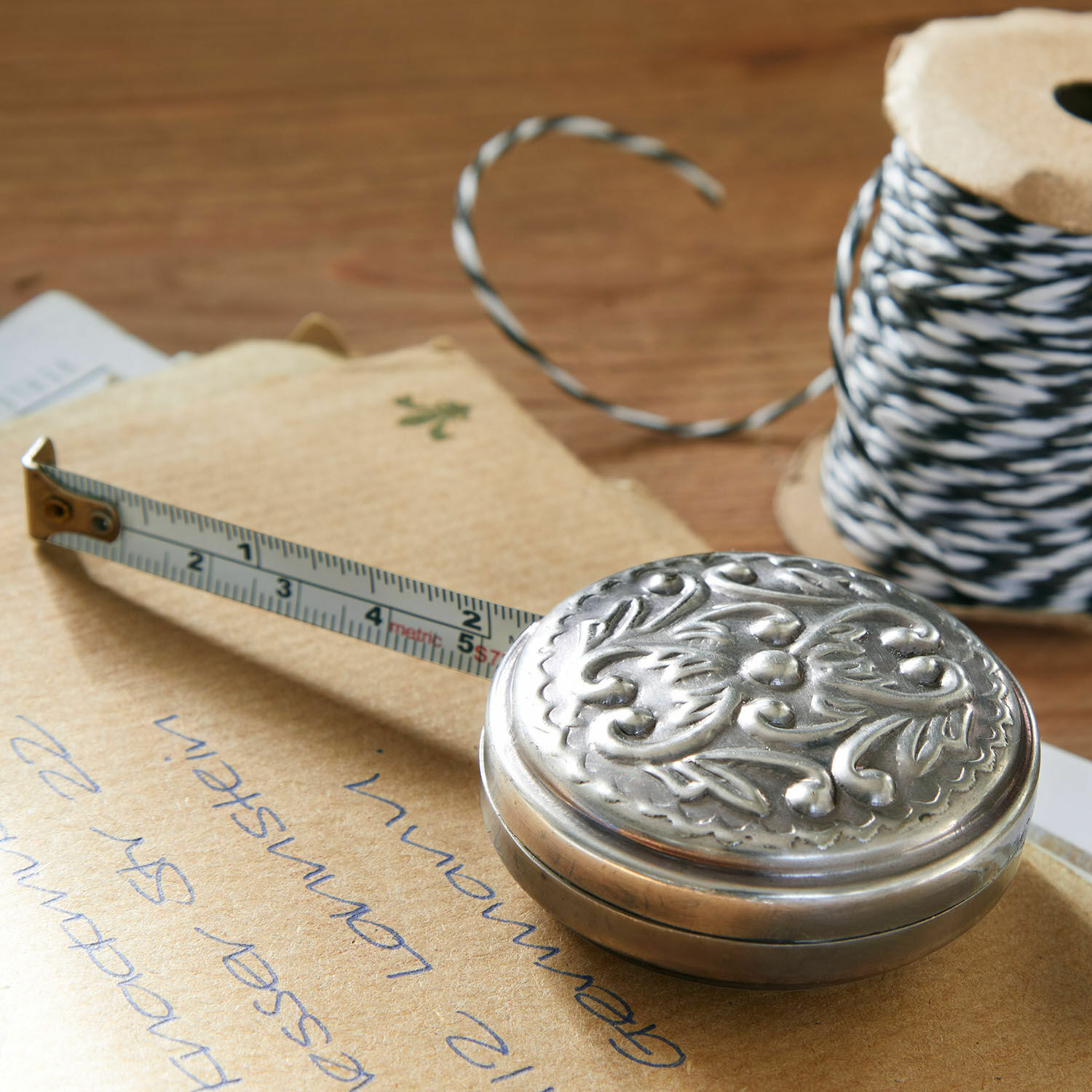 Metalen rolmaat met zilverkleurige versierde behuizing op houten tafel