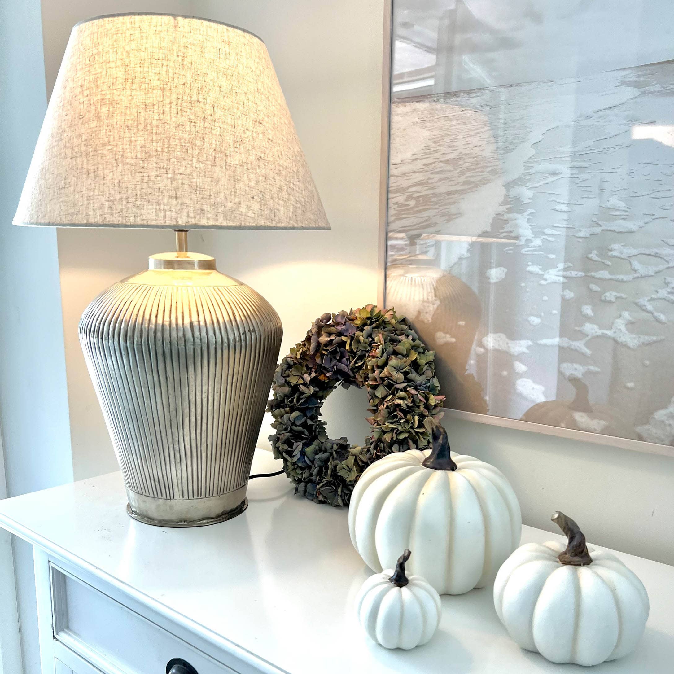 Tafellamp met beige kap en keramische voet, witte decoratieve pompoenen en gedroogde bloemenkrans