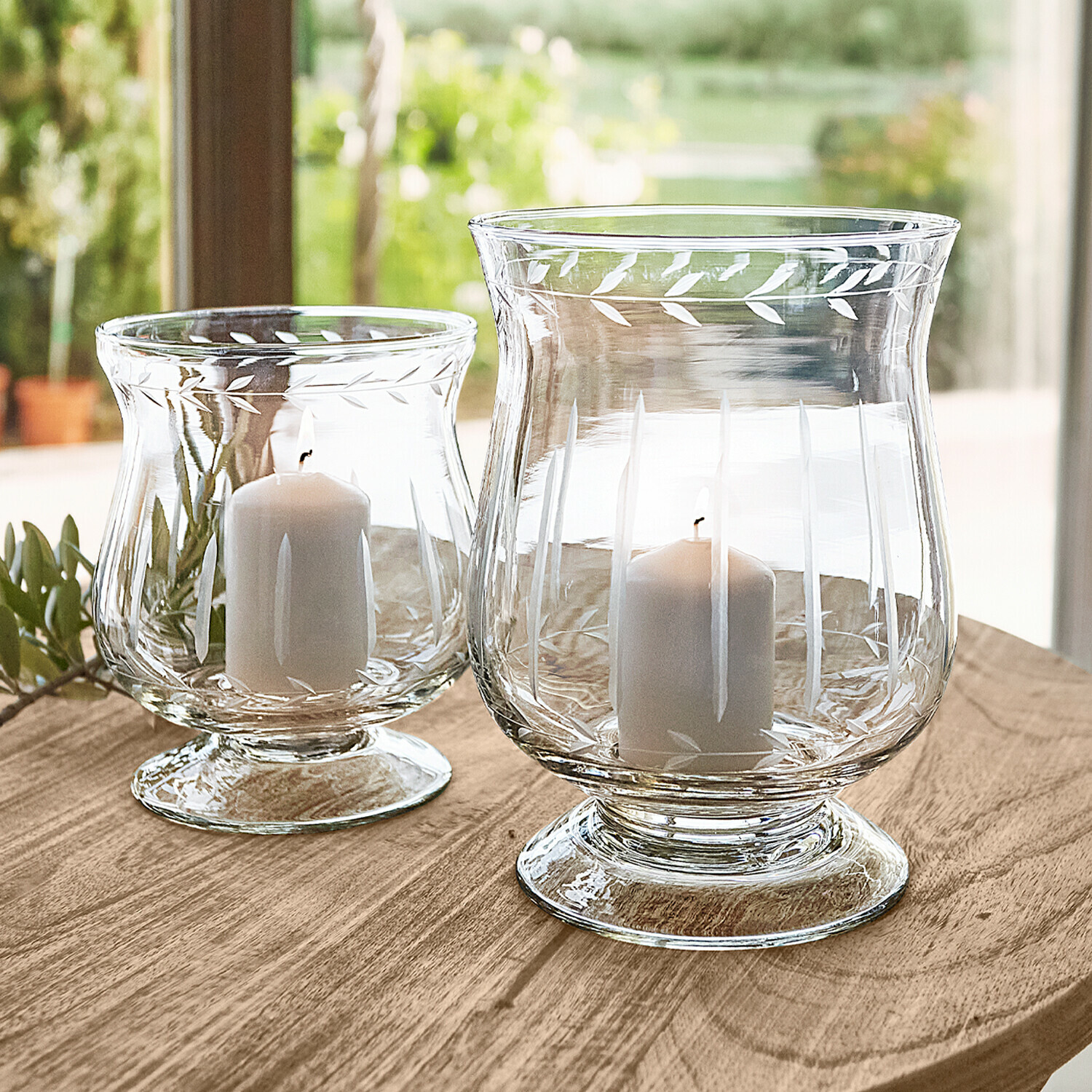 Windlicht set van 2 Moon Twee transparante glazen windlichten met witte kaarsen op houten tafel, decoratieve bladeren
