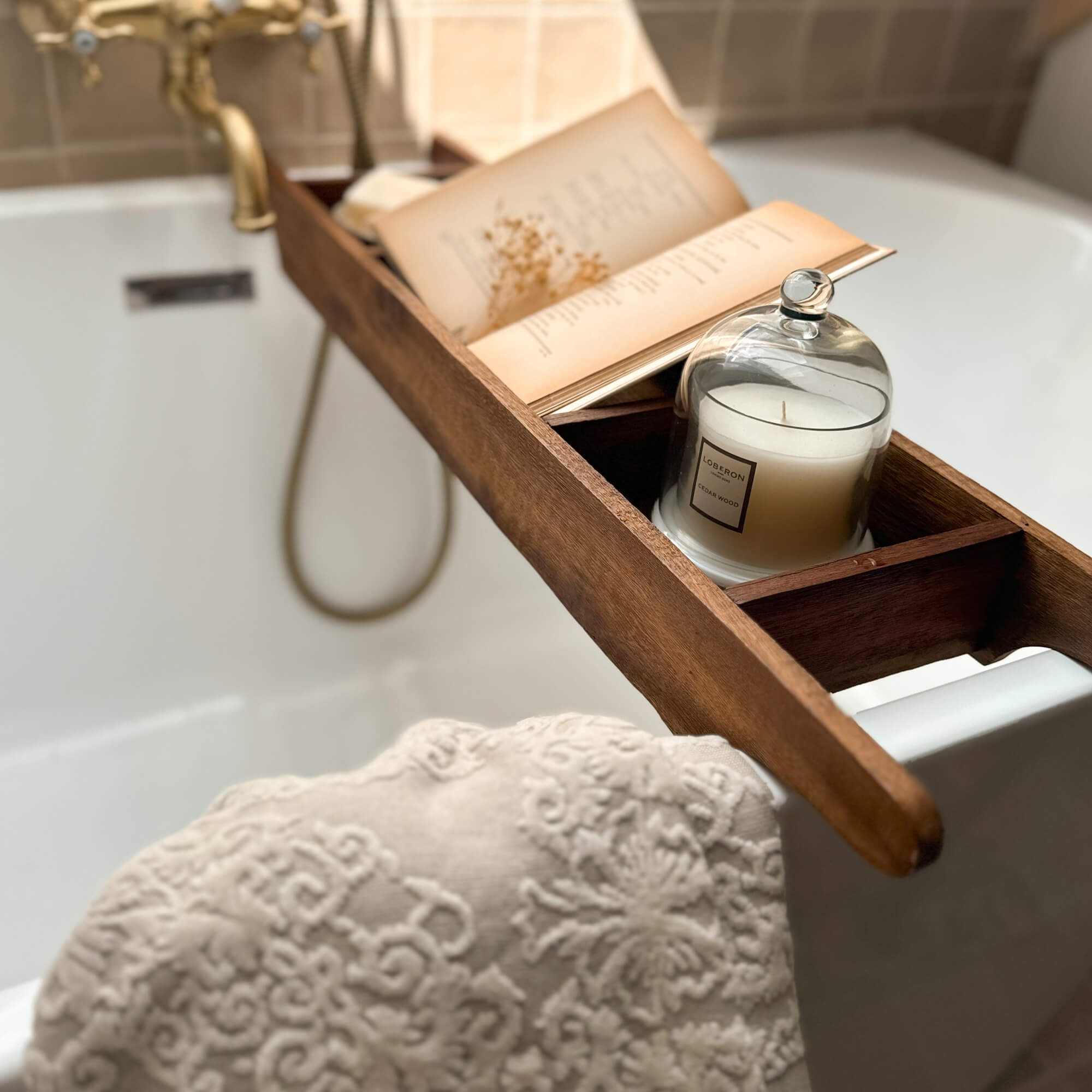 Houten badplank met witte kaars en open boek, ontspannend badkameraccessoire