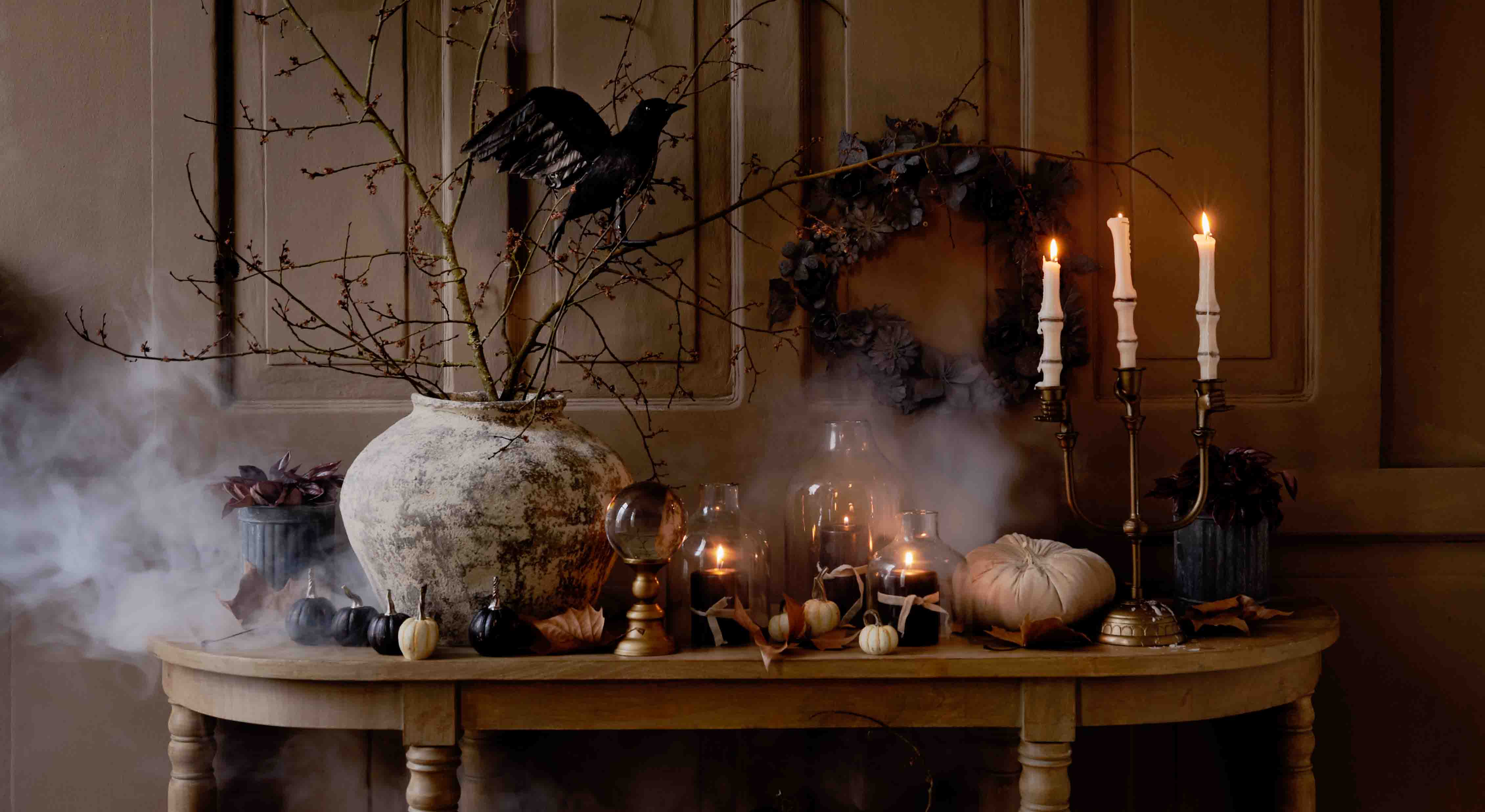 Rustieke tafel met herfstdecoratie van pompoenen, kaarsen en takken in keramische vaas, sfeerverlichting