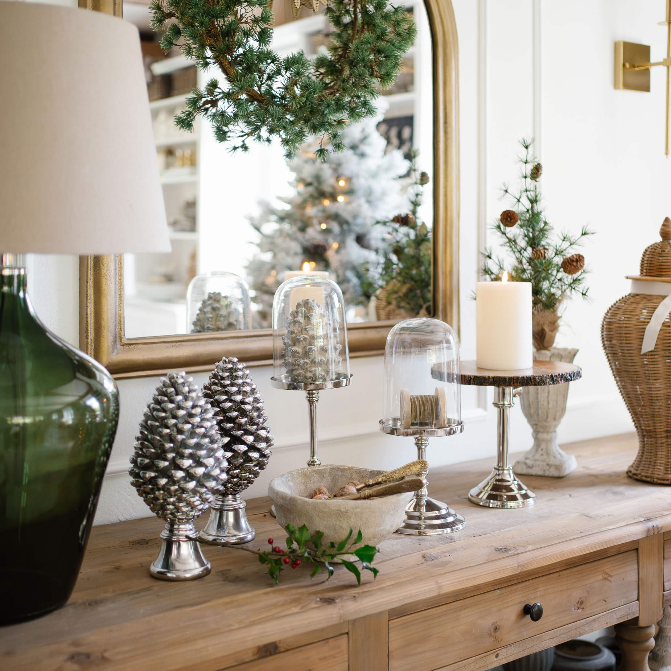Decoratieve zilveren dennenappels en kaars op houten tafel in rustiek interieur met groene accenten
