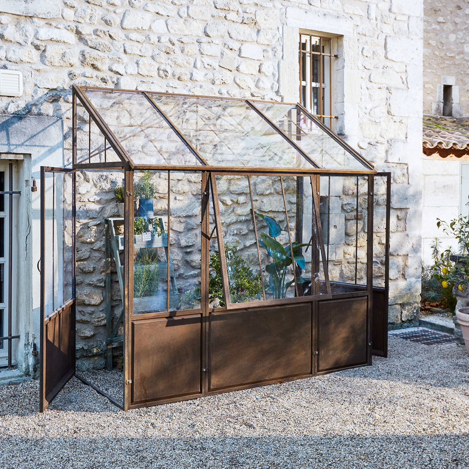 Plantenkas Essone Tuinserre met roestig metalen frame en glazen panelen, ideaal voor het kweken van planten en kruiden buiten