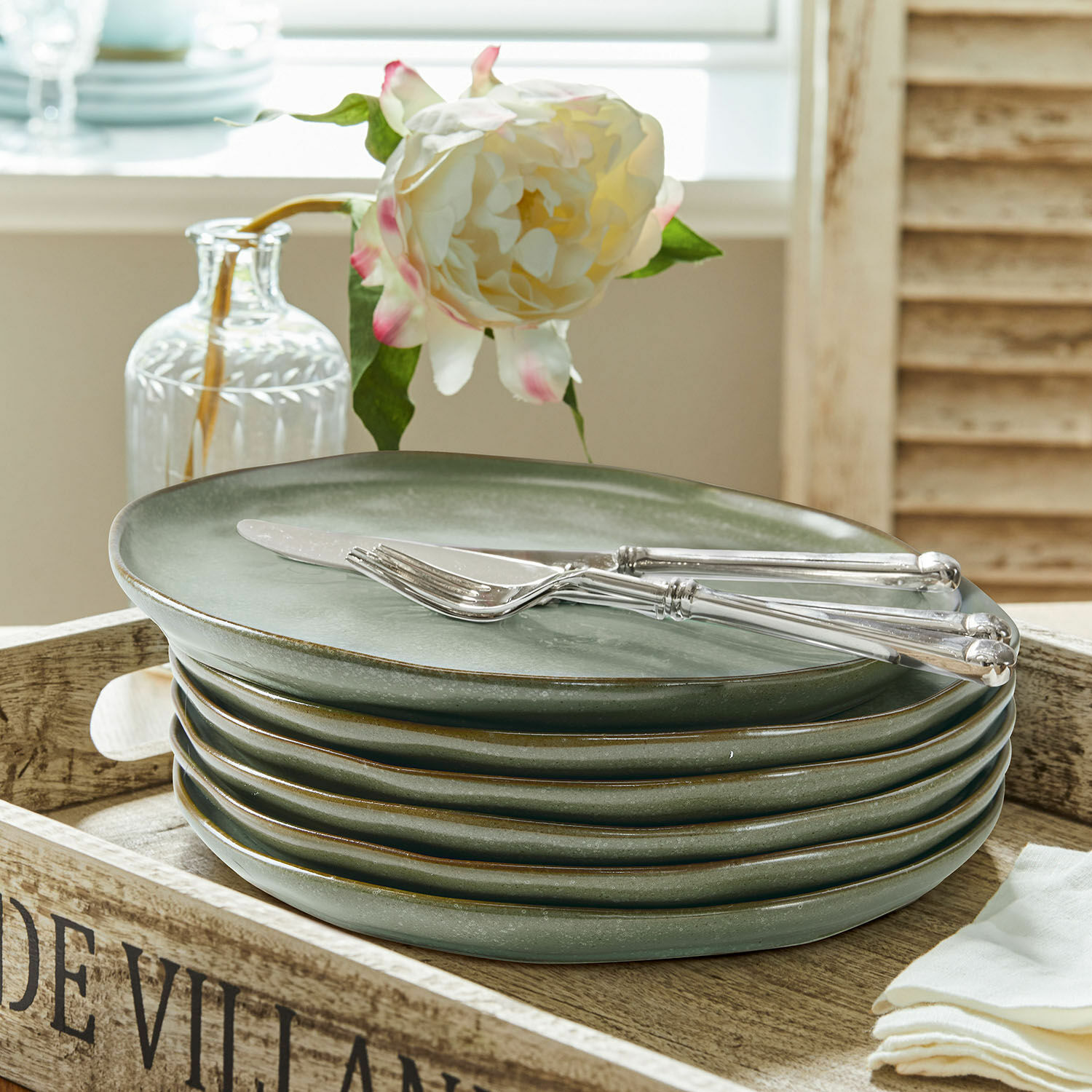 Set groene keramische borden op houten dienblad met mes en vork van roestvrij staal