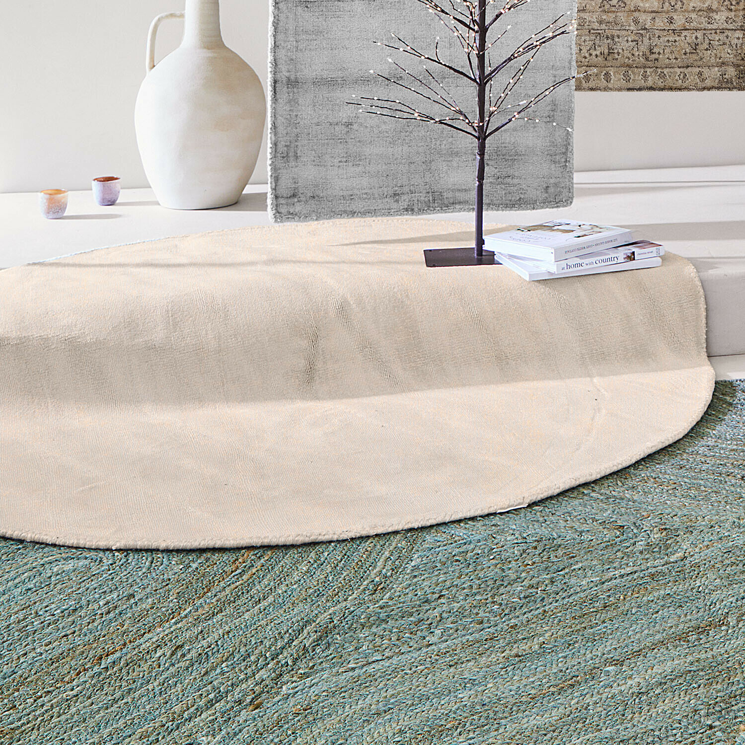 Ronde beige vloerkleed van natuurlijk materiaal op groen vloerkleed in modern interieur