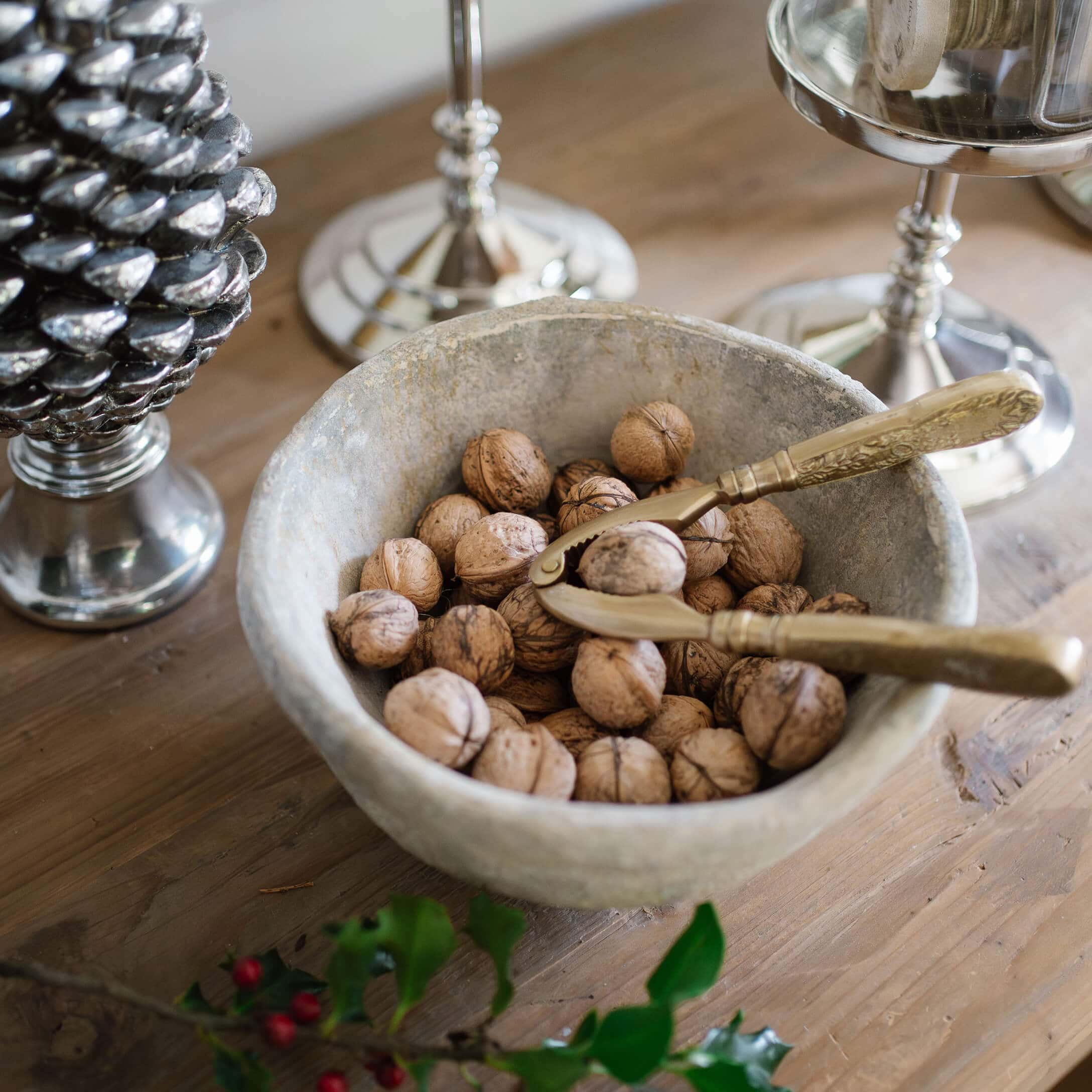 Steen kom met walnoten en gouden notenkraker op rustieke houten tafel