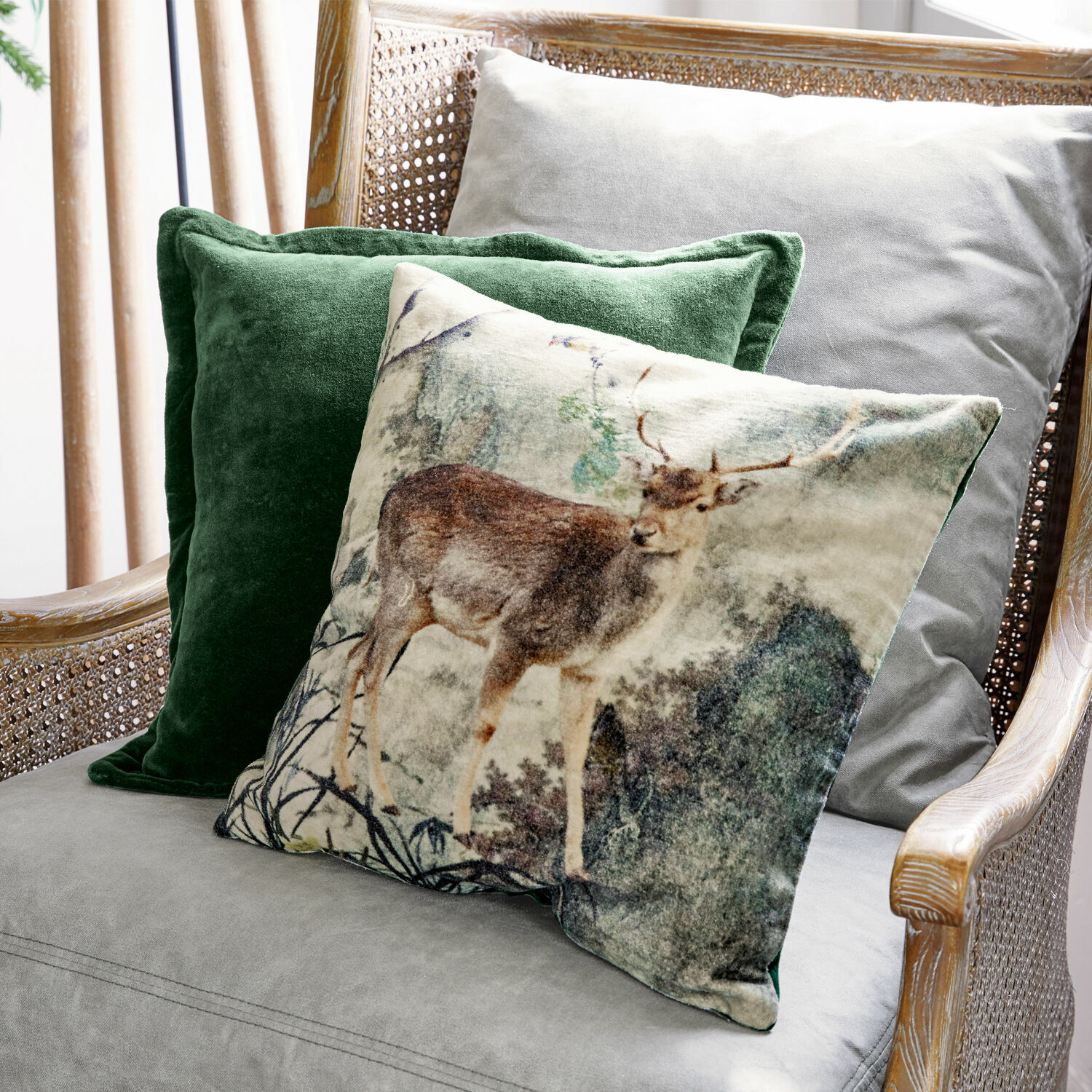 Set decoratieve kussens met hertmotief en groene fluweel op een grijze stoel