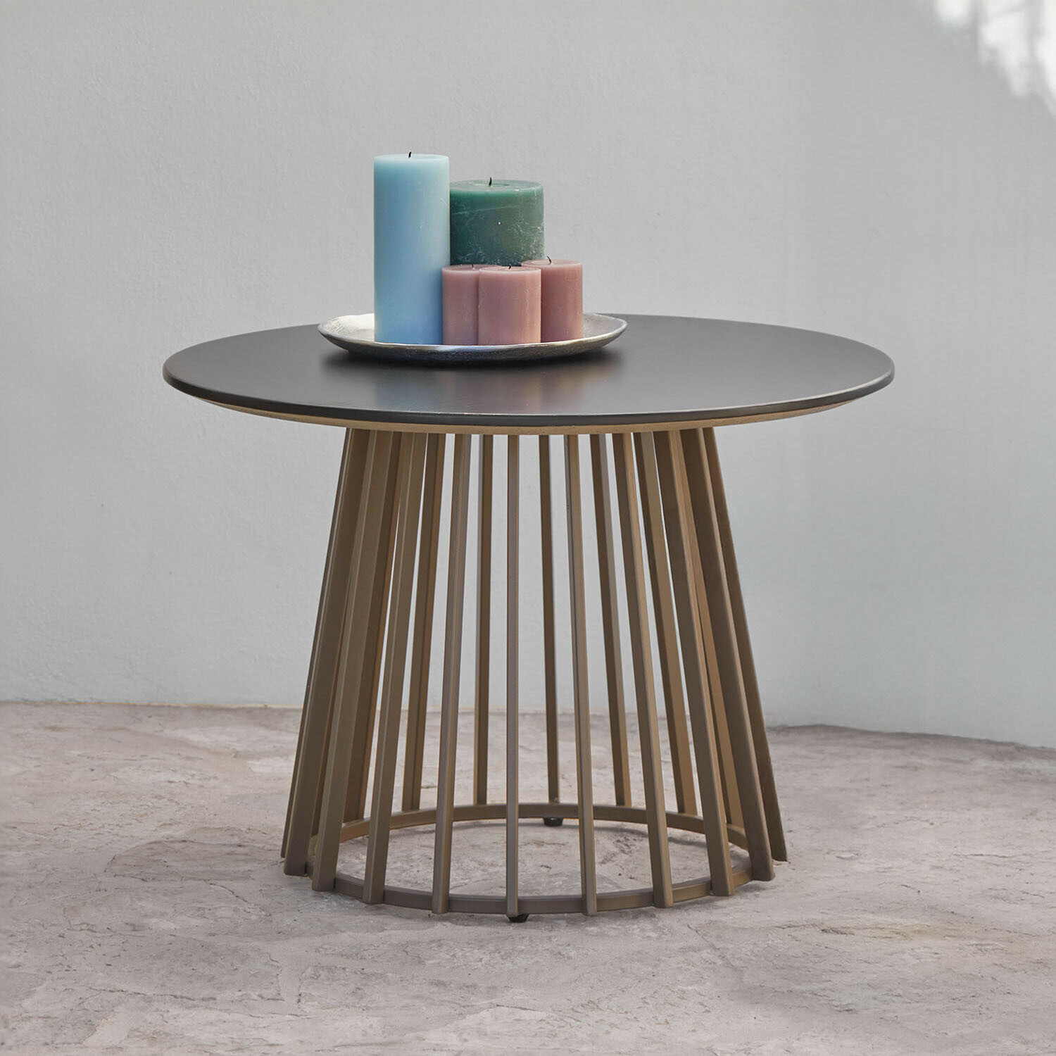 Ronde salontafel met zwart metalen blad en bruine stalen onderstel, versierd met gekleurde kaarsen