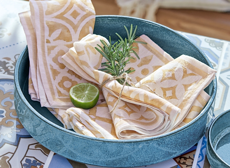 Blauwe keramische schaal met beige-witte linnen servetten en limoenpartje, mediterrane stijl