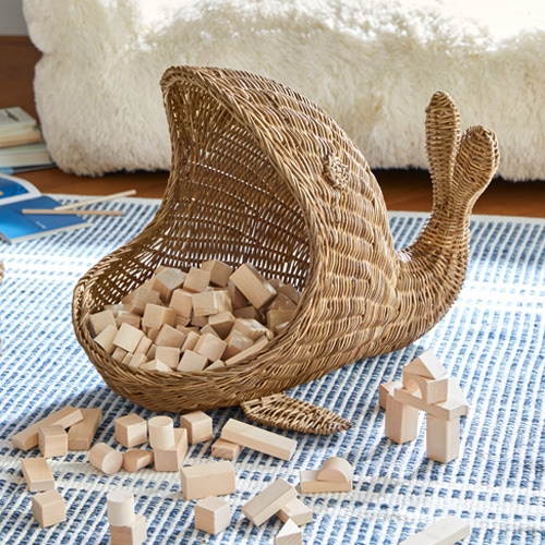 Rieten mand in de vorm van een slak met houten blokken op een blauw tapijt
