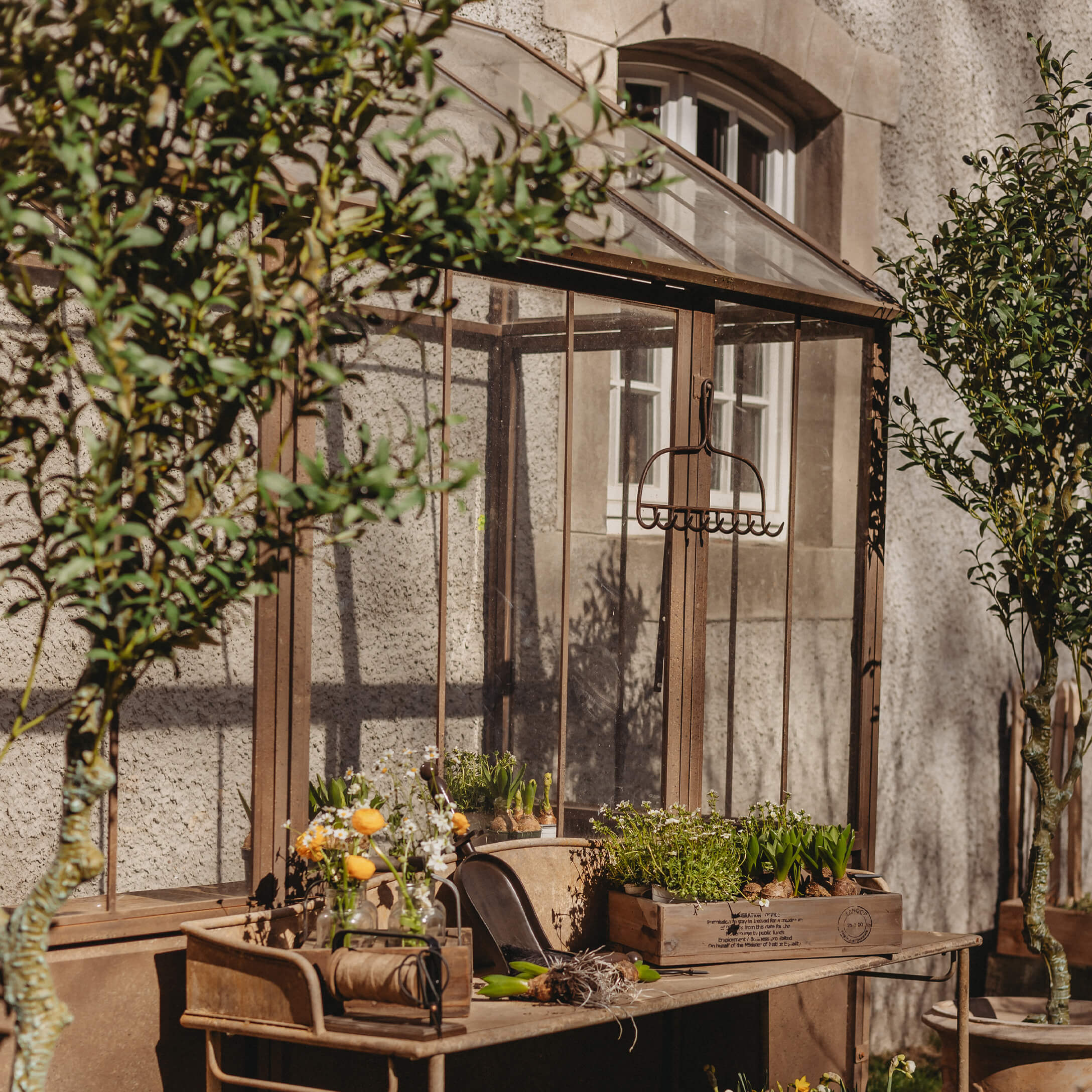Vintage metalen tuintafel met bloempotten en gereedschap voor een glazen kas