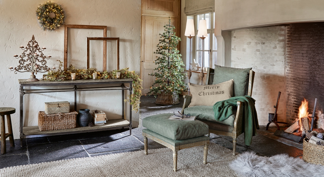 Gezellige woonkamer met groene stoel, brandende open haard en kerstdecoratie met boom en krans
