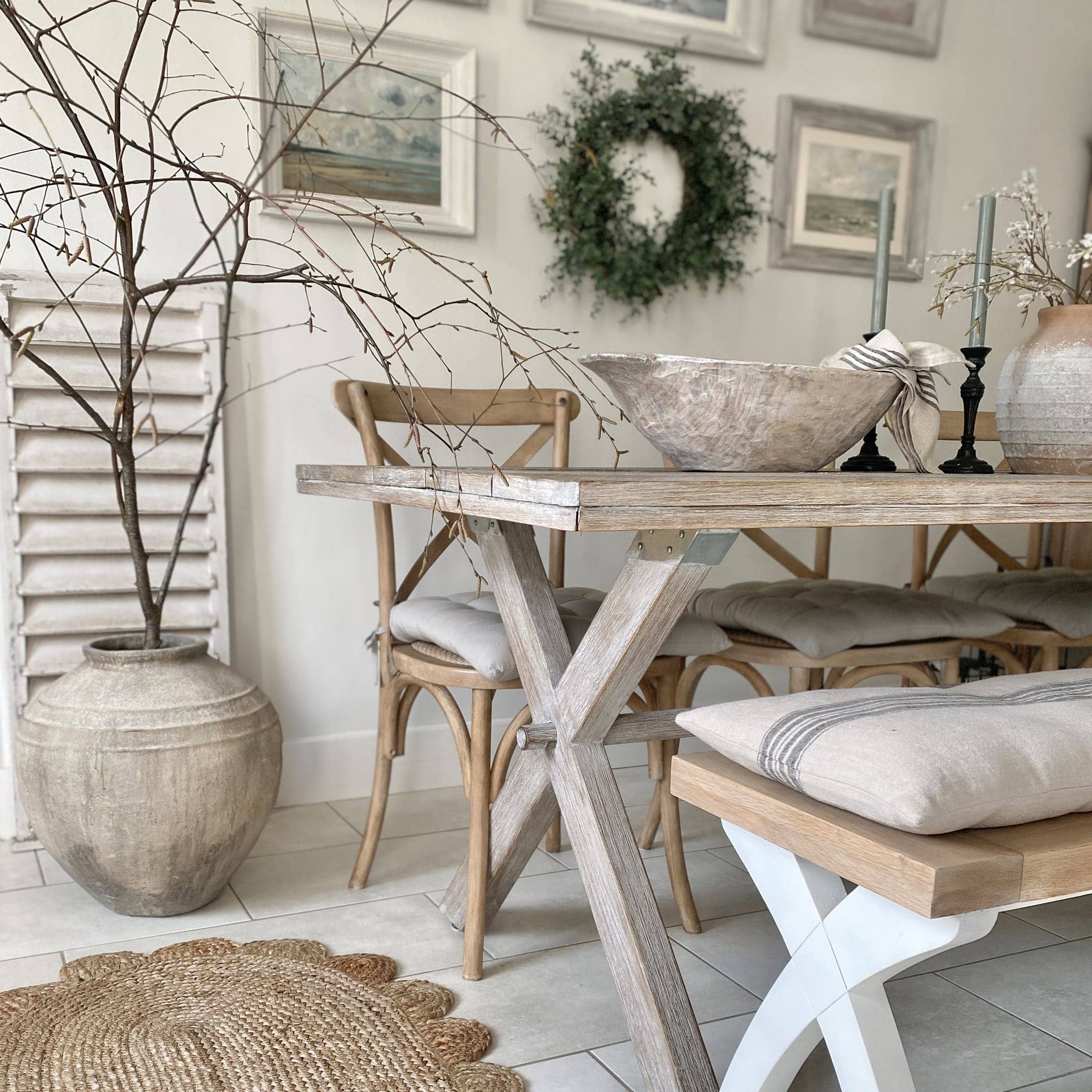 Eetkamer met lichte houten tafel, bijpassende stoelen, natuurlijke decoraties en kussens