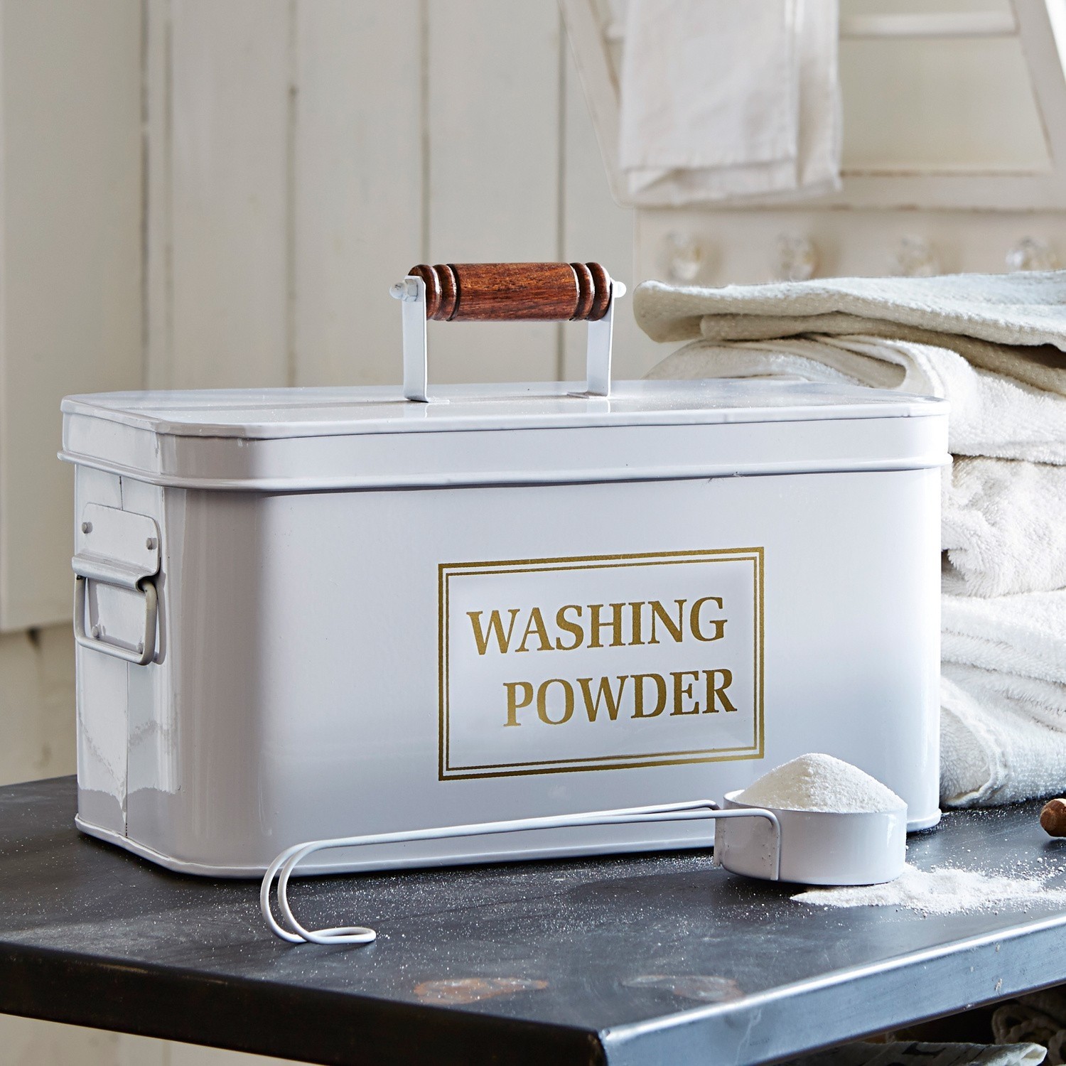 Wasmiddelblik Washing Witte metalen waspoedercontainer met houten handvat en maatlepel op zwarte tafel