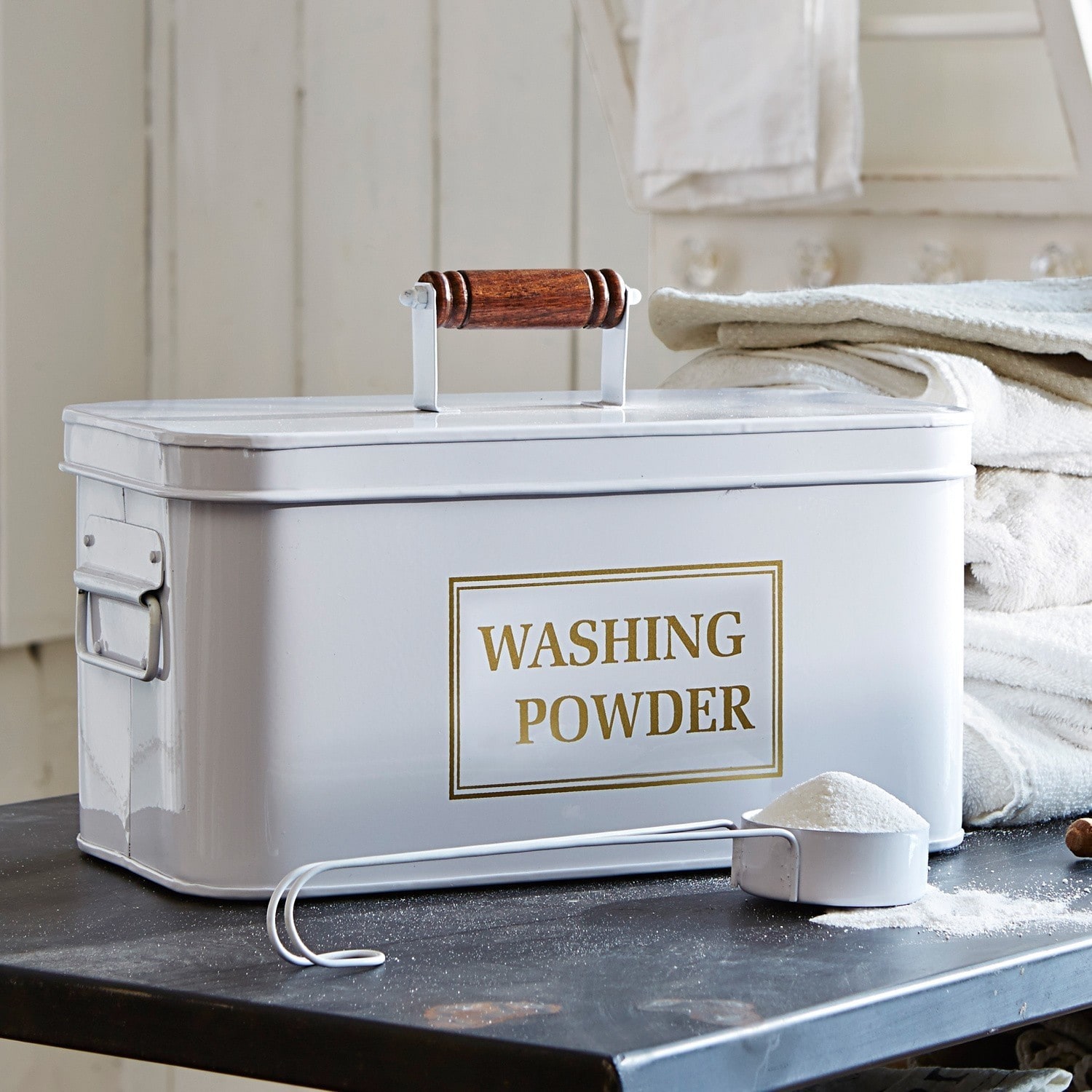 Wasmiddelblik Washing Witte metalen waspoedercontainer met houten handvat en maatlepel op zwarte tafel