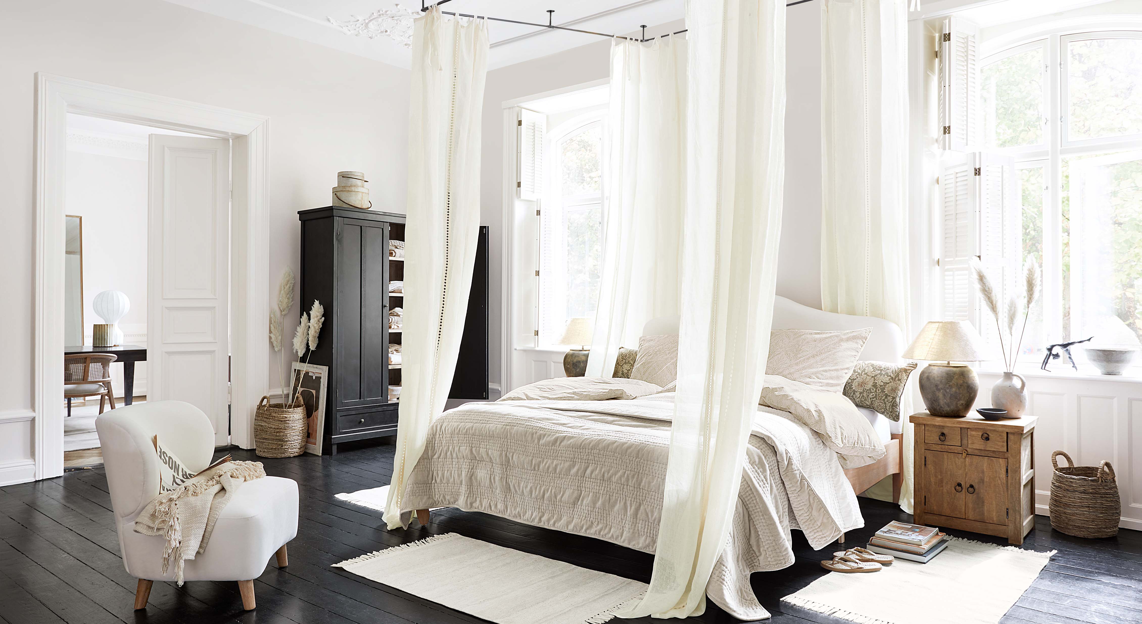 Gezellige slaapkamer met hemelbed, lichtbeige beddengoed en Scandinavische houten meubels