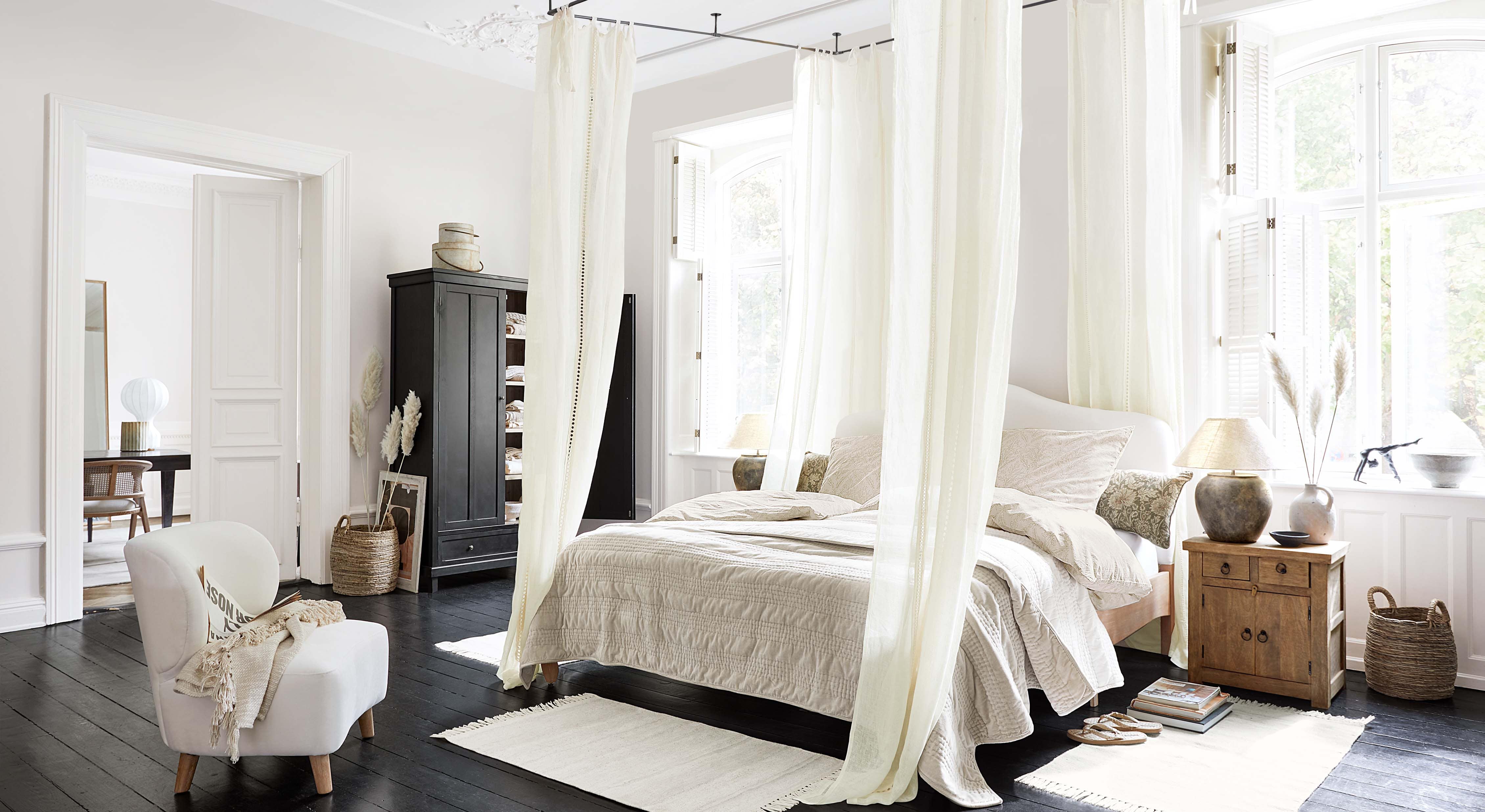 Gezellige slaapkamer met hemelbed, lichtbeige beddengoed en Scandinavische houten meubels