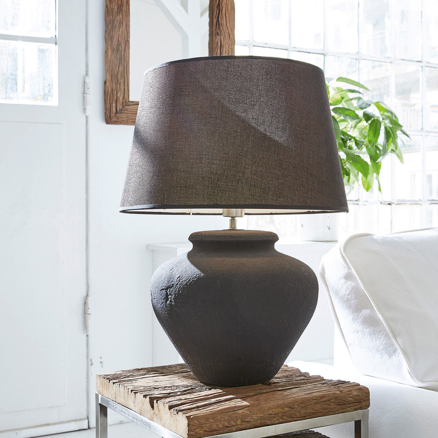Tafellamp Bandol Zwarte keramische tafellamp met stoffen kap op houten tafel in lichte kamer