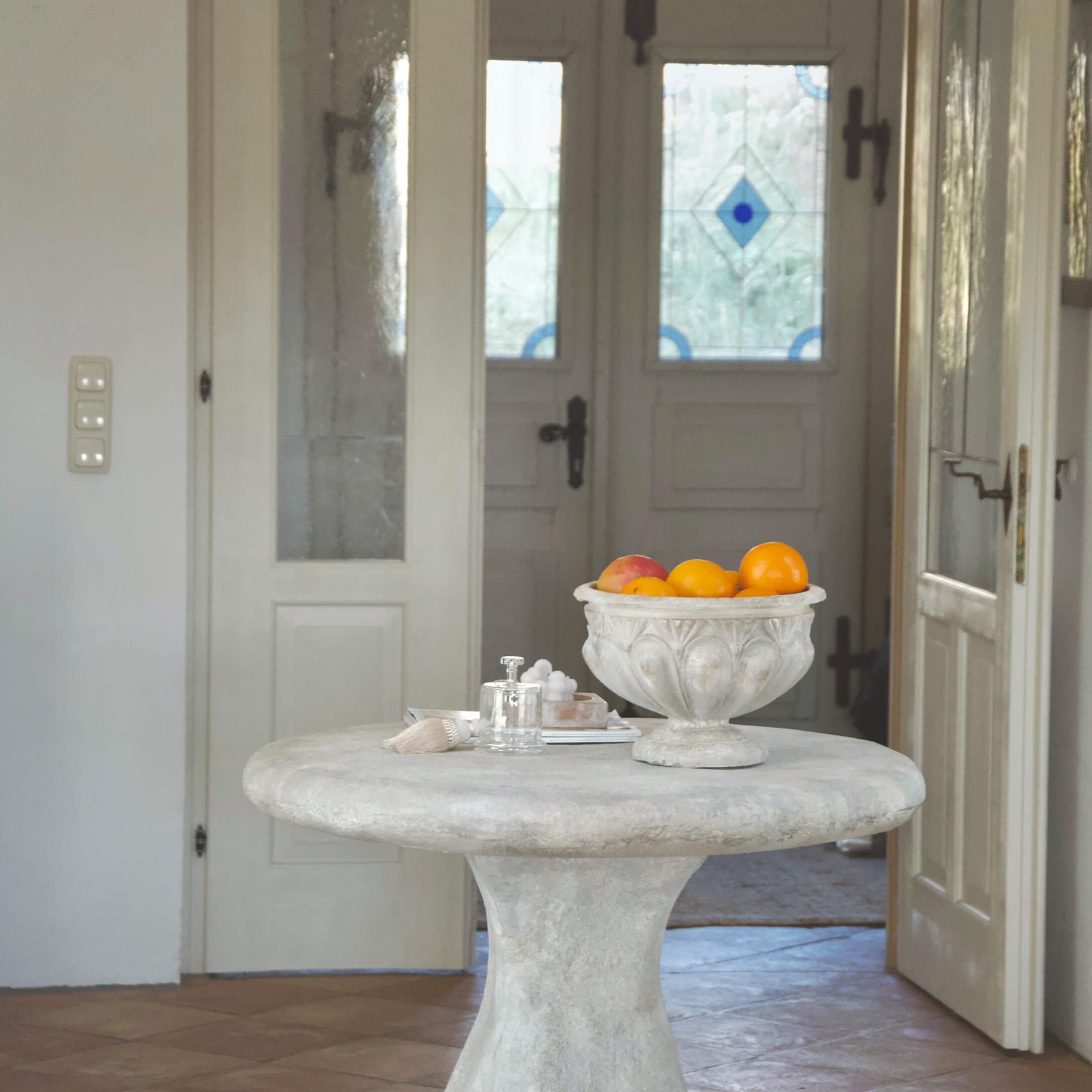 Ronde tafel van licht beton met decoratieve vintage schaal vol oranje fruit