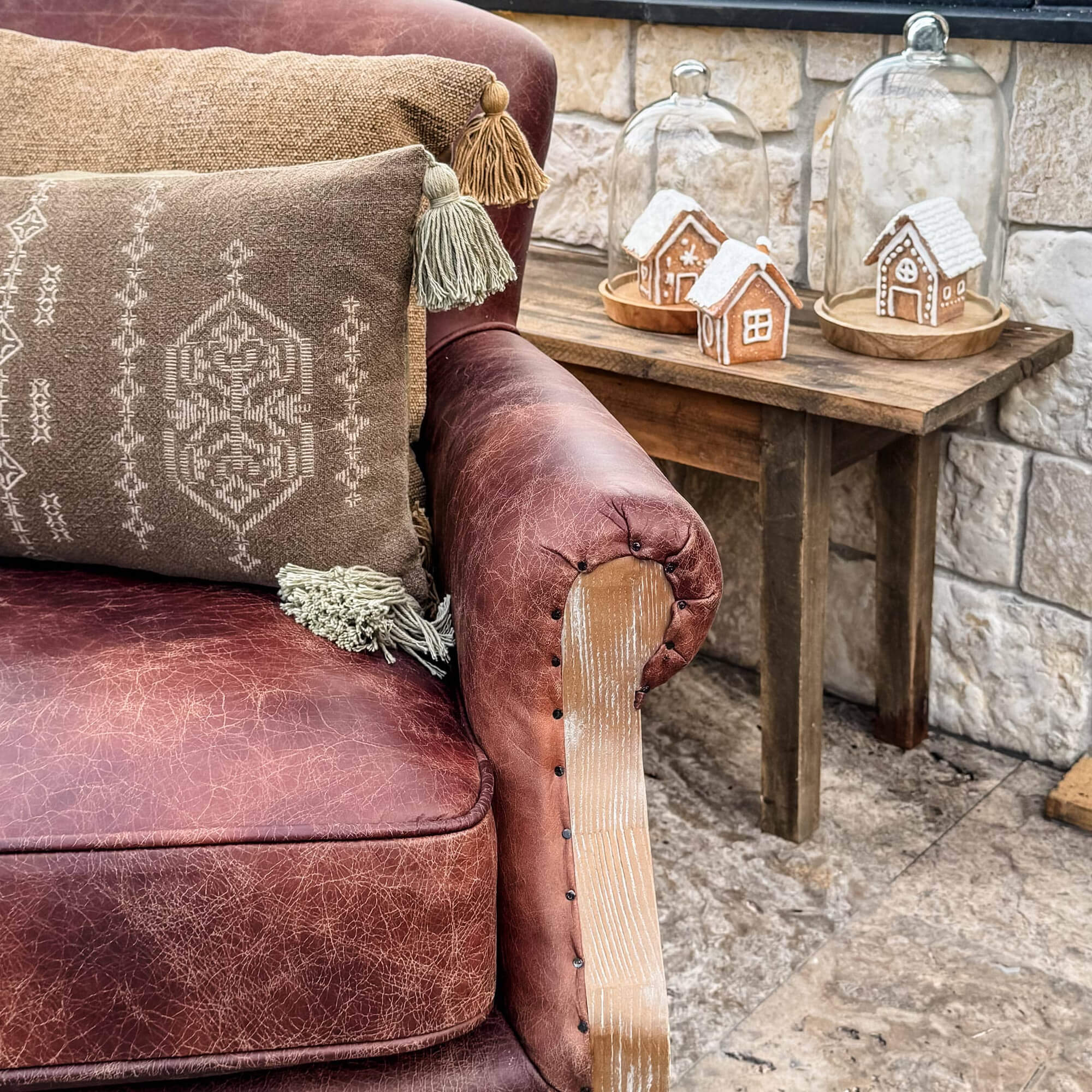 Bruine leren bank met decoratief kussen en houten tafel met peperkoekhuisjes onder glazen stolpen