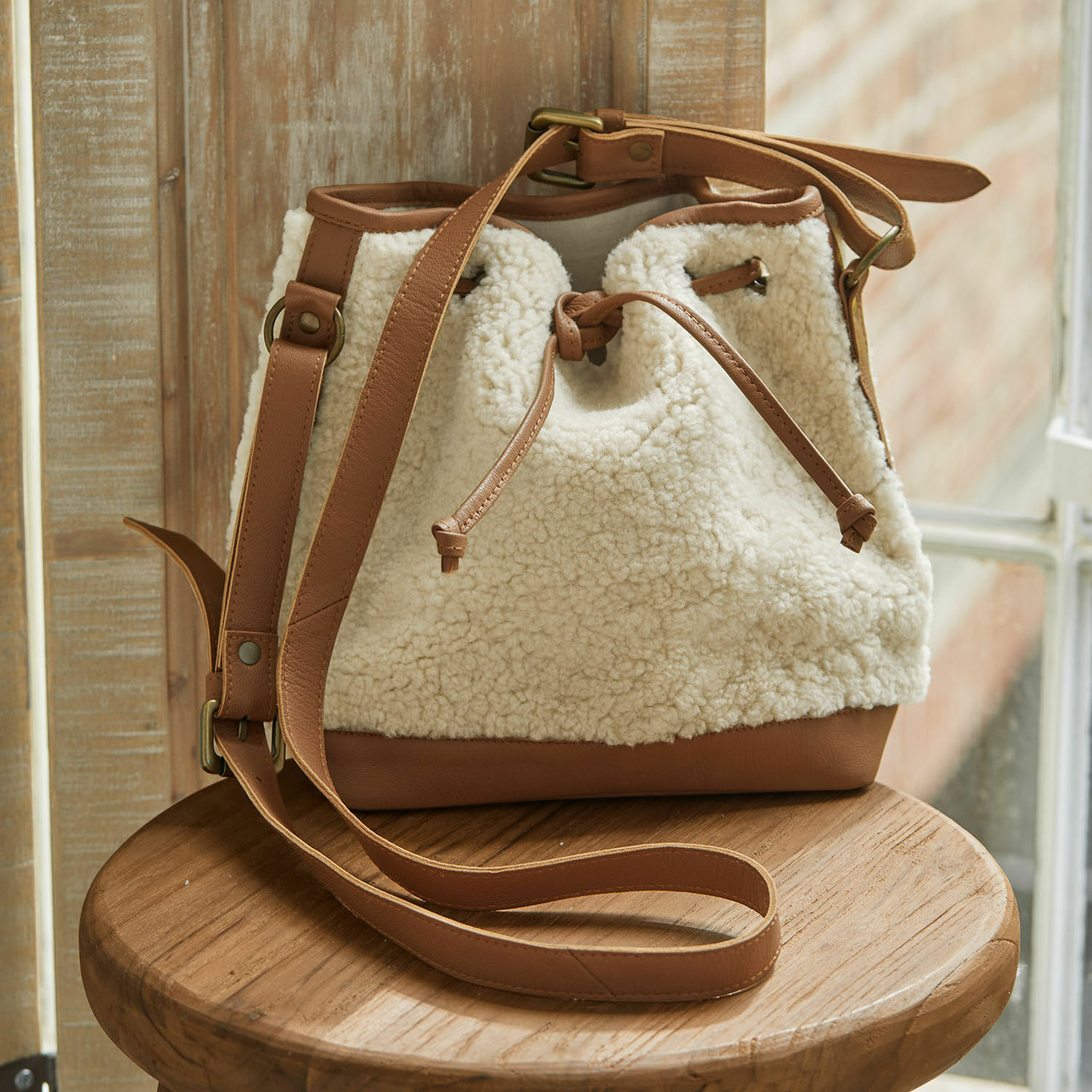 Tas Bellaros Beige buideltas van bruin leer en zacht materiaal dat op schapenvacht lijkt, modieuze accessoire