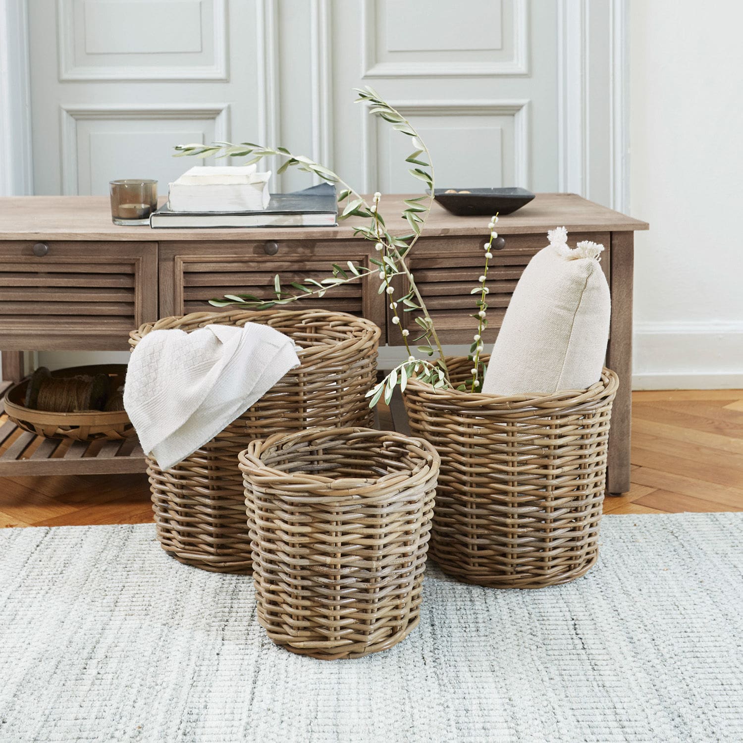 Mand set van 3 Avar Set van drie natuurlijke rieten manden voor thuisopslag op een lichte vloerkleed.