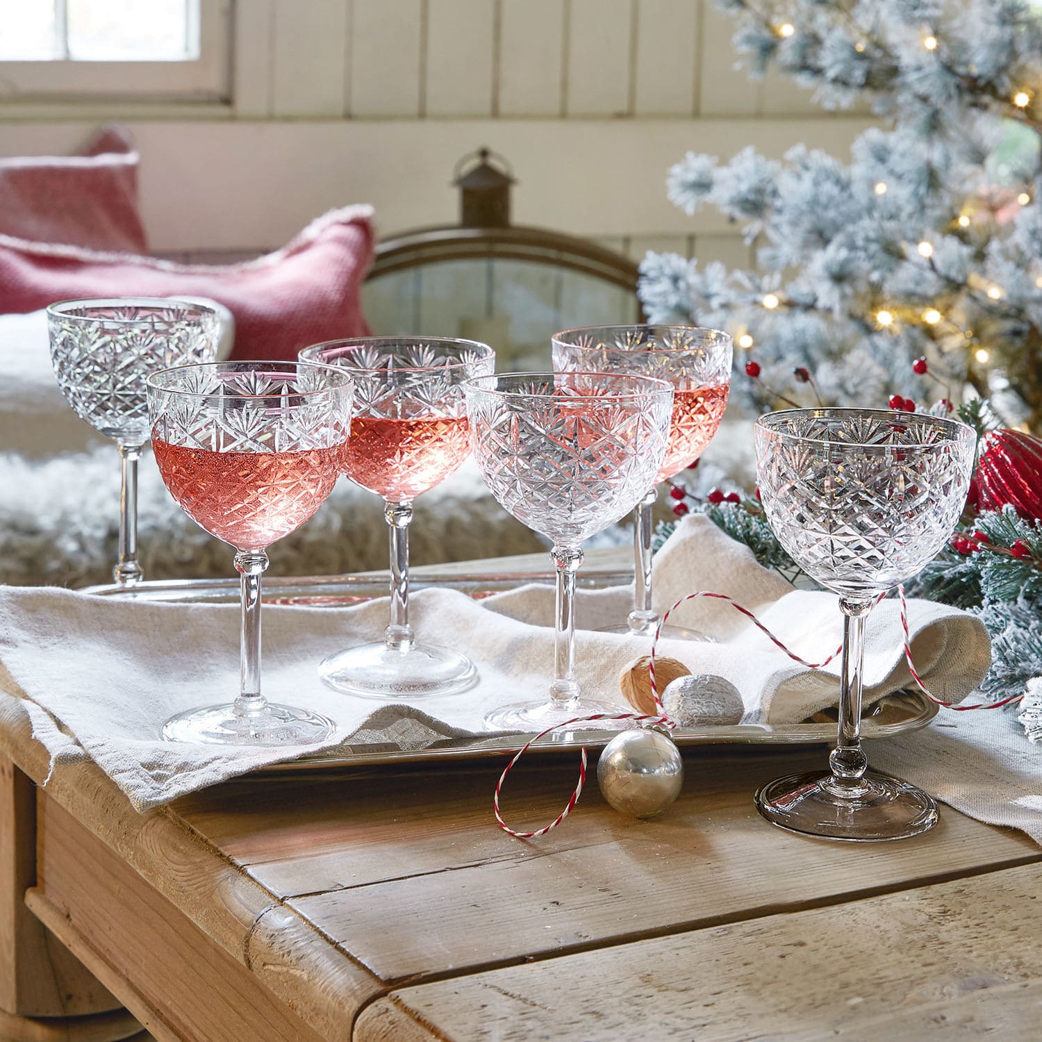Champagneglas set van 6 Olite Set van zes kristallen wijnglazen met geslepen patroon, deels gevuld met roséwijn, feestelijke setting