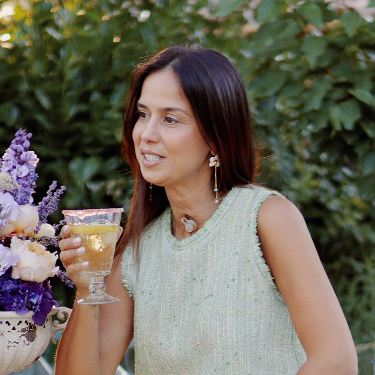 Vrouw in groene mouwloze trui met glas drank voor groene achtergrond met bloemen