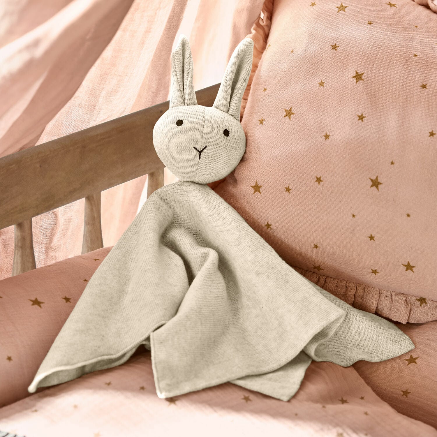 Knuffeldier Lumiou Zachte grijze stoffen konijnenknuffel op roze beddengoed met sterren, kinderkamerdecoratie